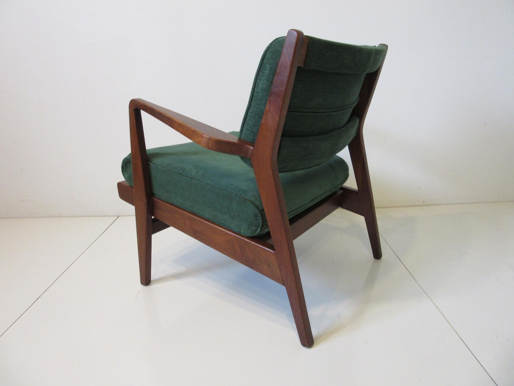 An early walnut framed low lounge chair with upholstered back and bottom cushion in a soft comfortable forest green material. Having flared armrests and nice splayed styled legs giving the piece that very well designed and constructed look typical