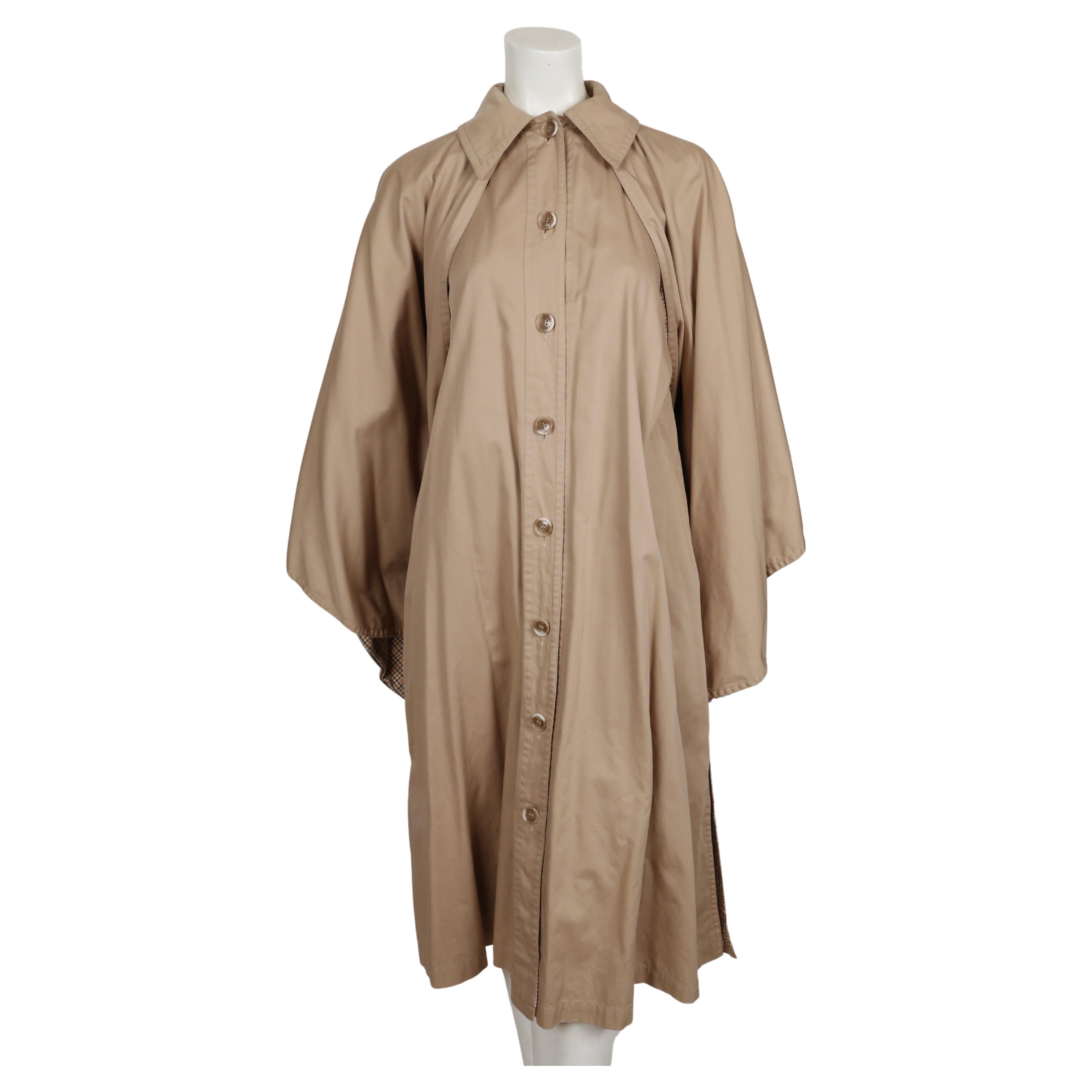Tan, cotton poplin trench coat with cape designed by Yves Saint Laurent dating to the early 1970's. No size is indicated however this fits many sizes due to the loose cut. Approximate measurements:  bust 38