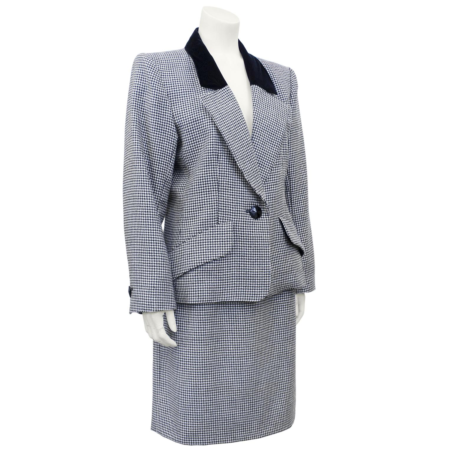 YSL Rive Gauche skirt suit from the early 1980s. Black and white wool houndstooth with contrasting black velvet collar detail. Classic blazer with a notched lapel, should pads, a single black button and slanted flap pockets at hips. Single black