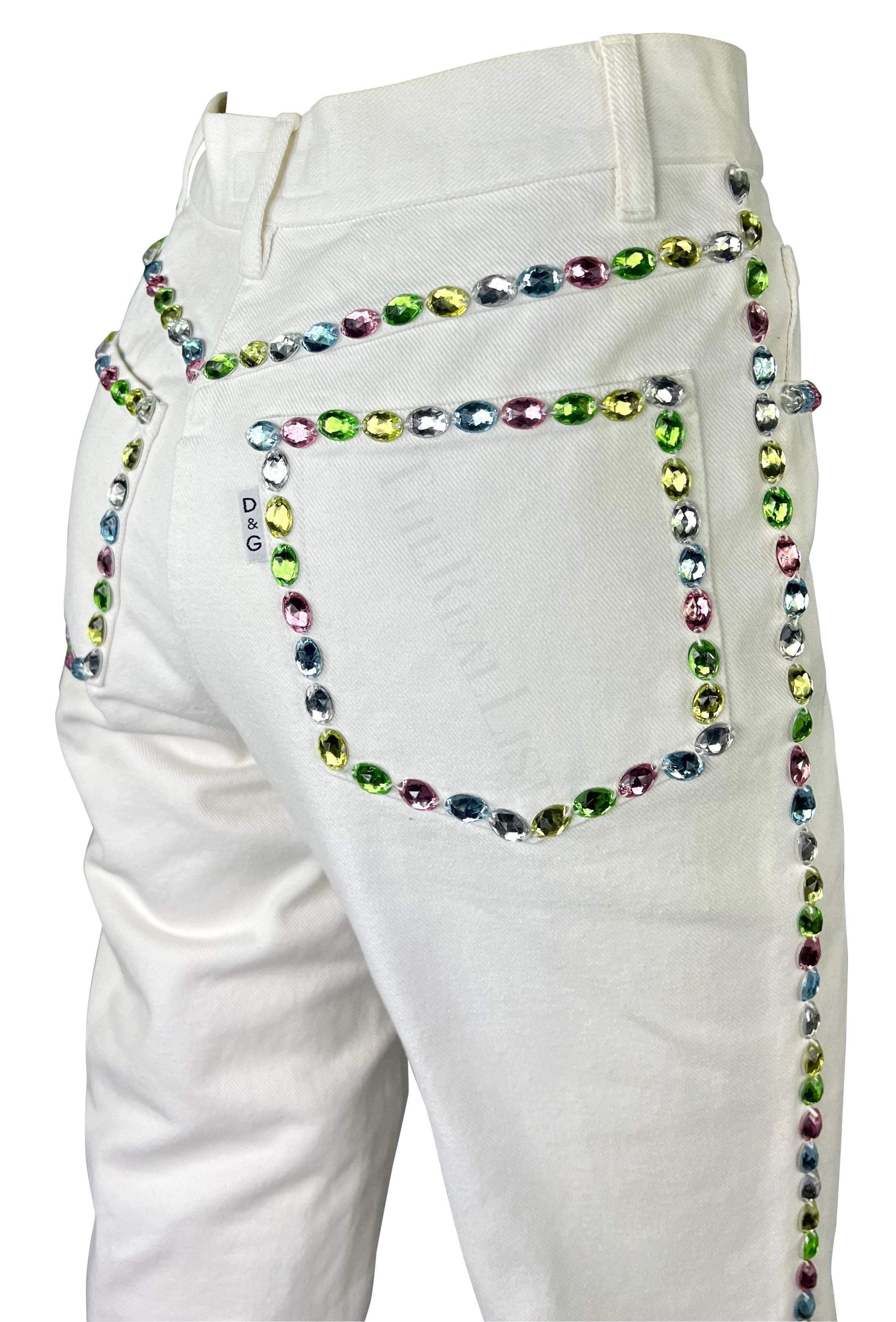 Whiting présente un pantalon Dolce & Gabbana en denim blanc orné de strass. Datant du début des années 1990, ce pantalon en denim à taille haute est rehaussé de strass de couleurs pastel variées qui accentuent les coutures du pantalon. Ce jean blanc