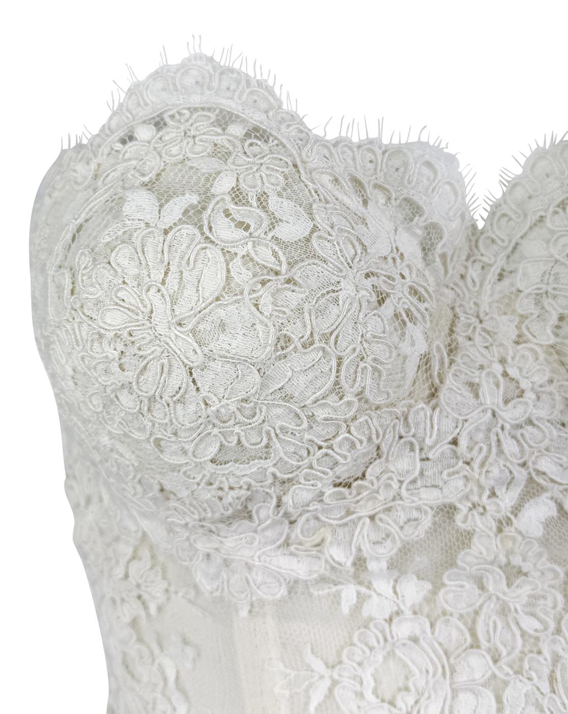 From the early 1990s, this Donna Karan strapless bustier top is crafted from sheer white lace with intricate an floral motif. Structured with internal boning for a sculpted, corset-like fit, the design features a sweetheart neckline and scalloped