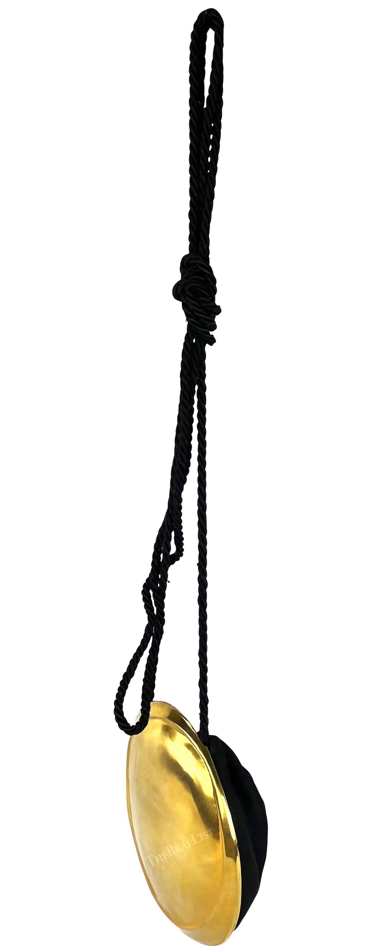 Magnifique sac de soirée Donna Karan en métal doré datant du début des années 1990. Ce petit sac présente un large extérieur en métal doré et comprend une petite pochette noire à cordon sur le côté opposé. Le sac est complété par une poignée en