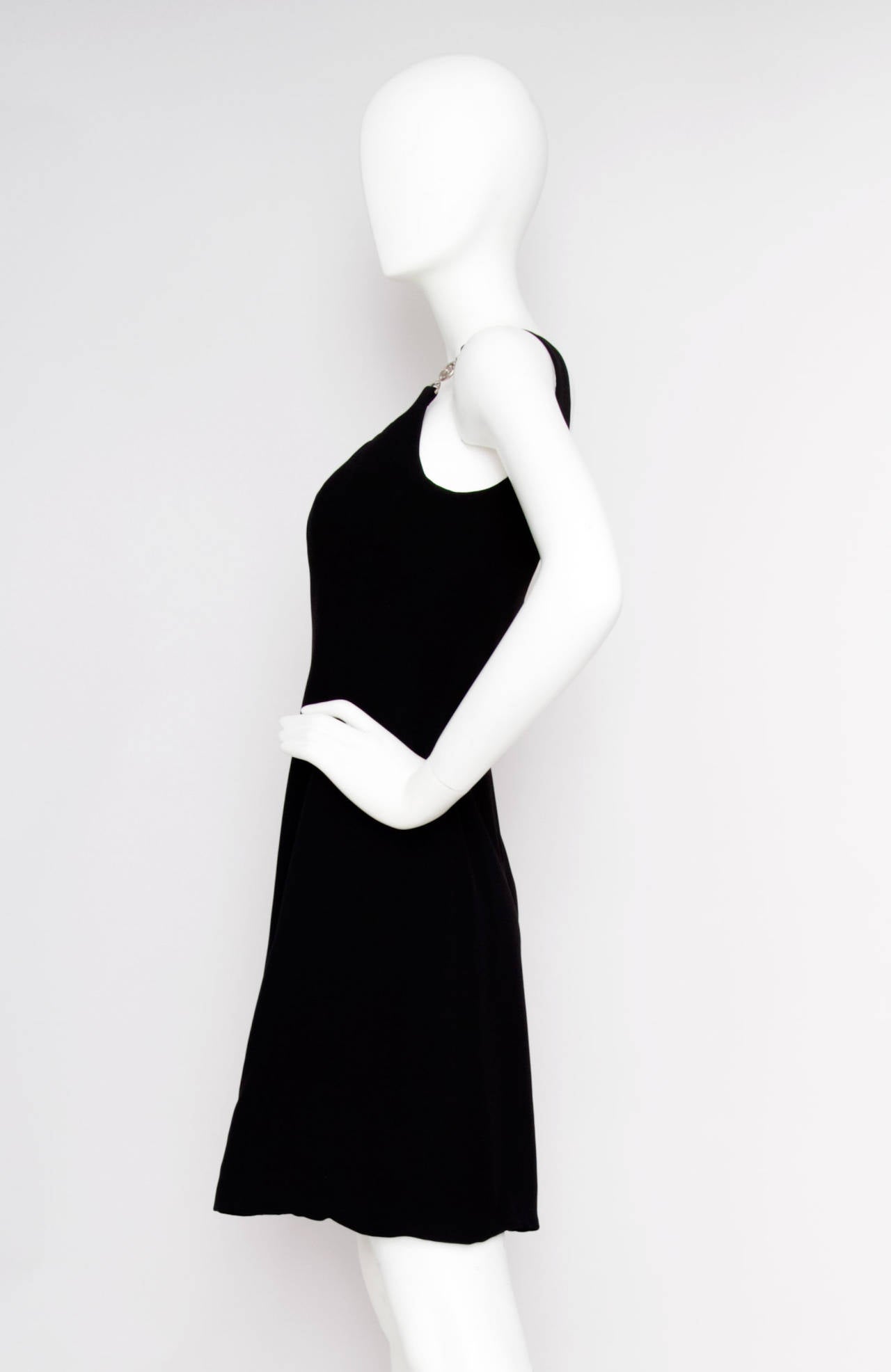 A 1960s inspired 1990s Vesace black mini dress, labelled: “Gianni Versace Couture” in black silk crêpe, structured bodice and silvertone Medusa-head buckles.

The dress is equivalent to a modern size Small.