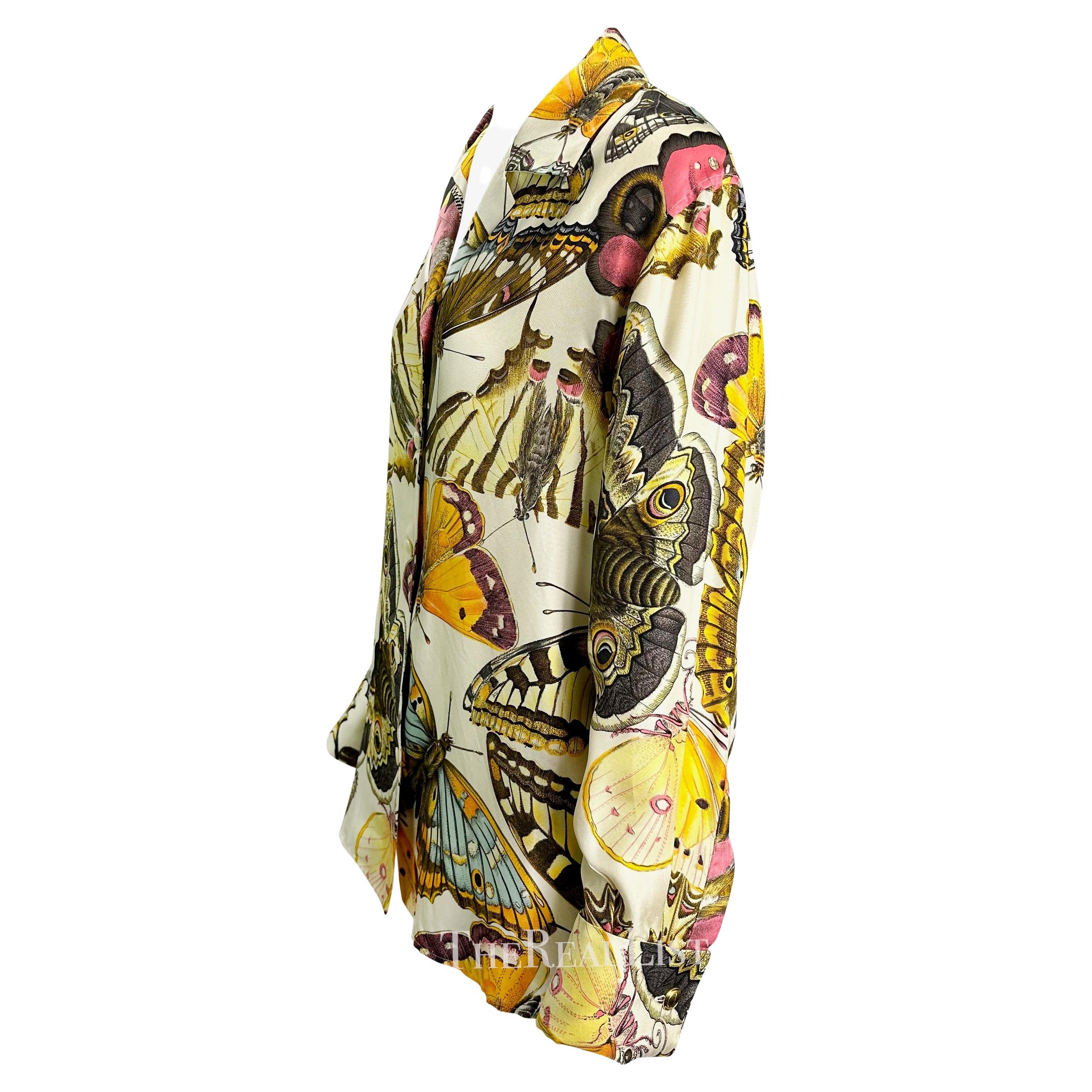 Ti presentiamo una bellissima camicia di seta Gucci con stampa a farfalla. Questo top dei primi anni '90 è realizzato in seta e presenta una grande stampa multicolore di farfalle e falene. Questo favoloso top è completato da grandi bottoni 