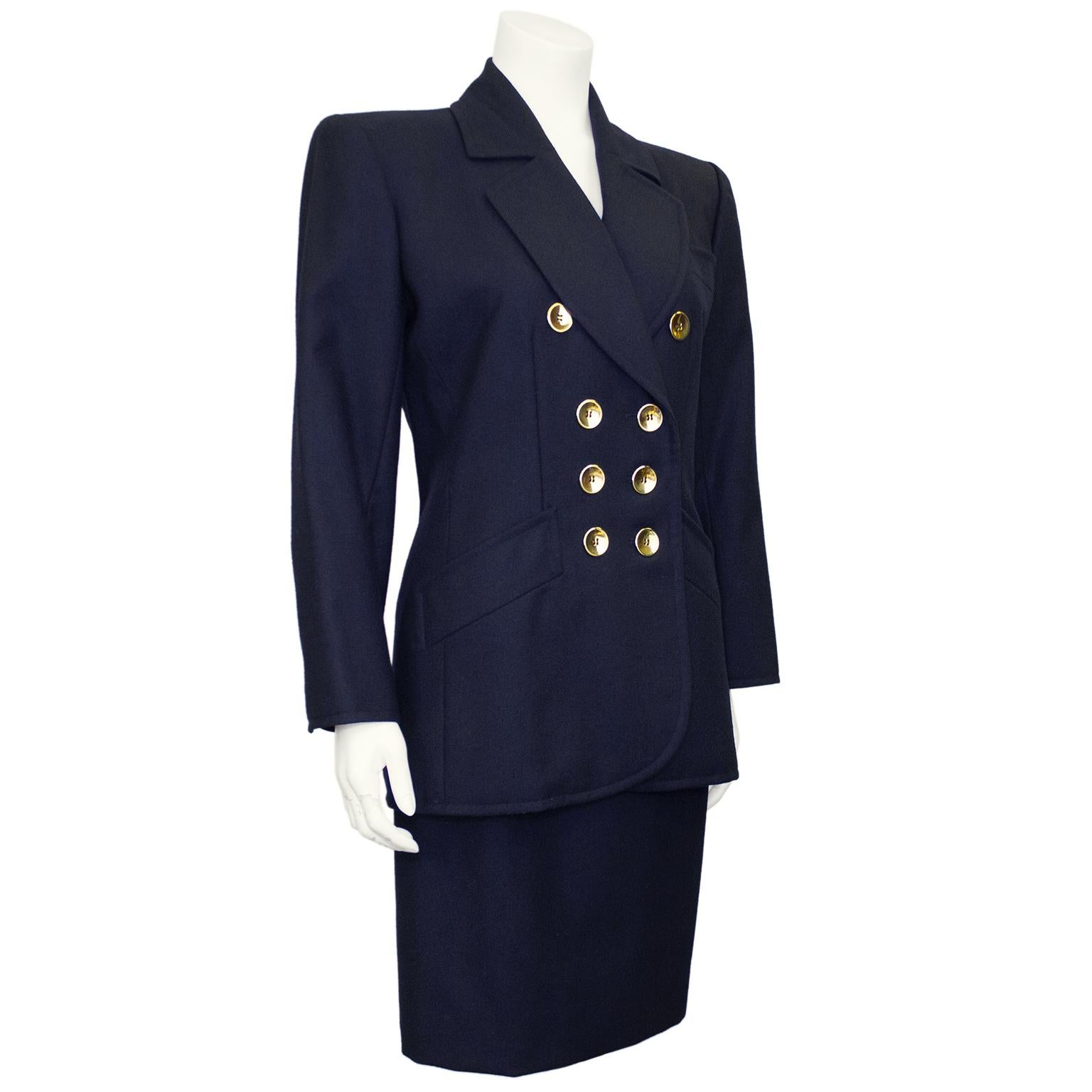 1990s Yves Saint Laurent Rive Gauche skirt suit in a dark navy wool. A classic style power suit; the jacket features shoulder pads and double breasted gold buttons down the front as well as on the cuffs with slit pockets on the hips. The notched