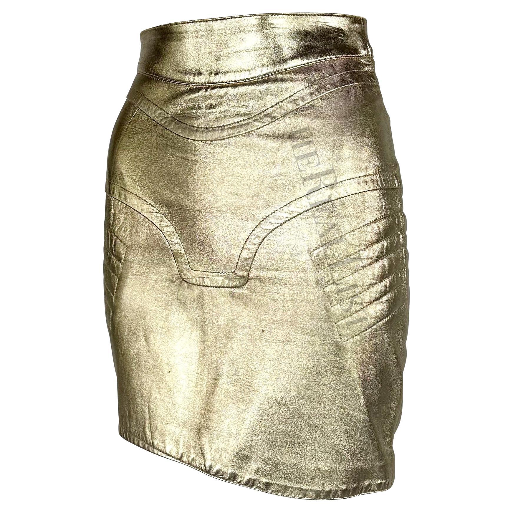 Presenting a fabulous gold-tone leather Thierry Mugler skirt. From the late 1980s / early 1990s, this skirt features an asymmetrical hem, a slit at the side, and motocross-style stitching. A perfect encapsulation of Mugler's sexy abstract style,