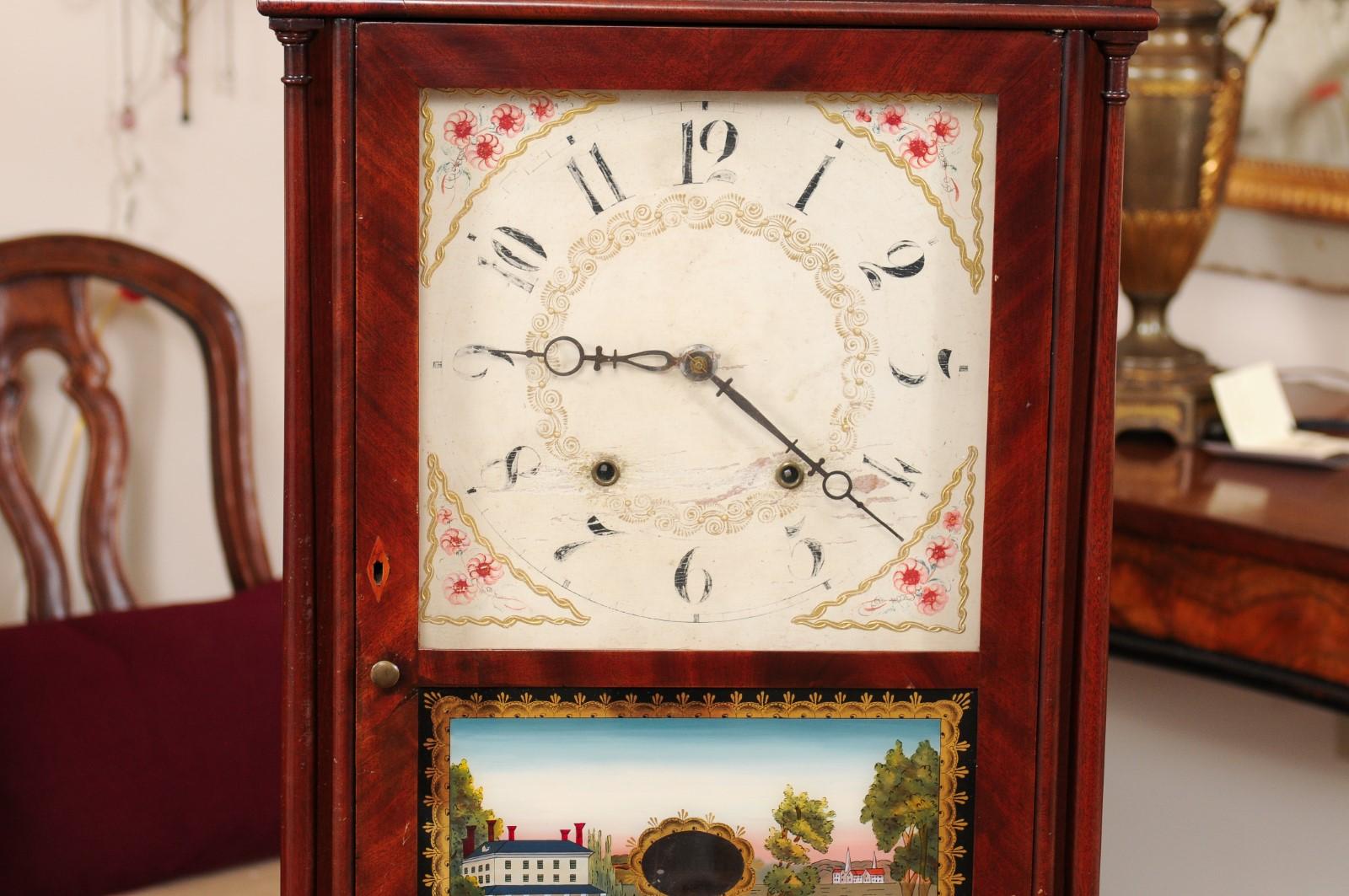 XIXe siècle Horloge à colonne et à volutes en acajou avec paysage en églomisé, début du 19e C. en vente