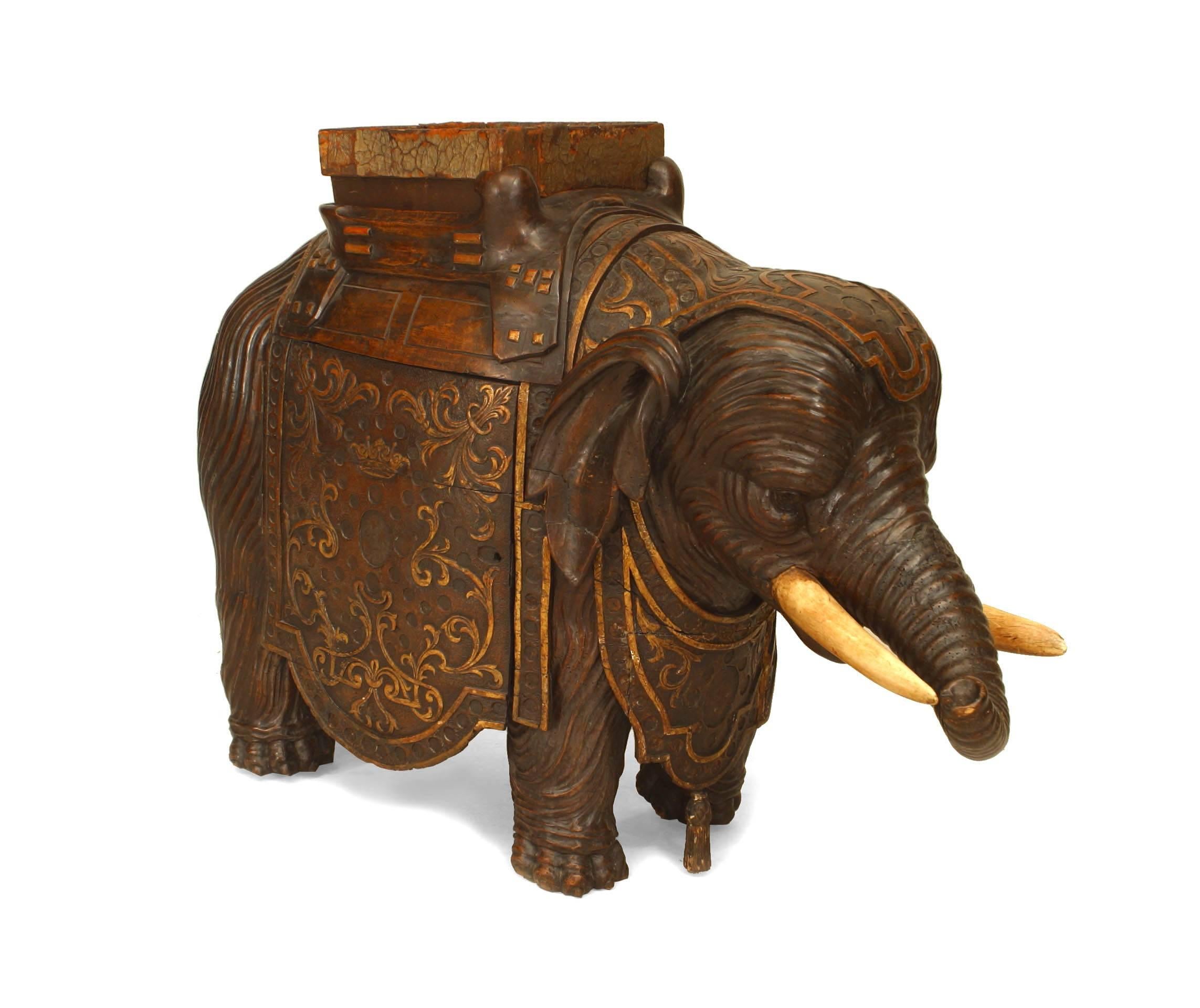 Anglo-Indian Walnut figure of an elephant dating to the English Regency period of the nineteenth century. Enshrouded in a decorative garb relief, the figure supports a square leather insert in the shape of a saddle and conceals three shelves behind