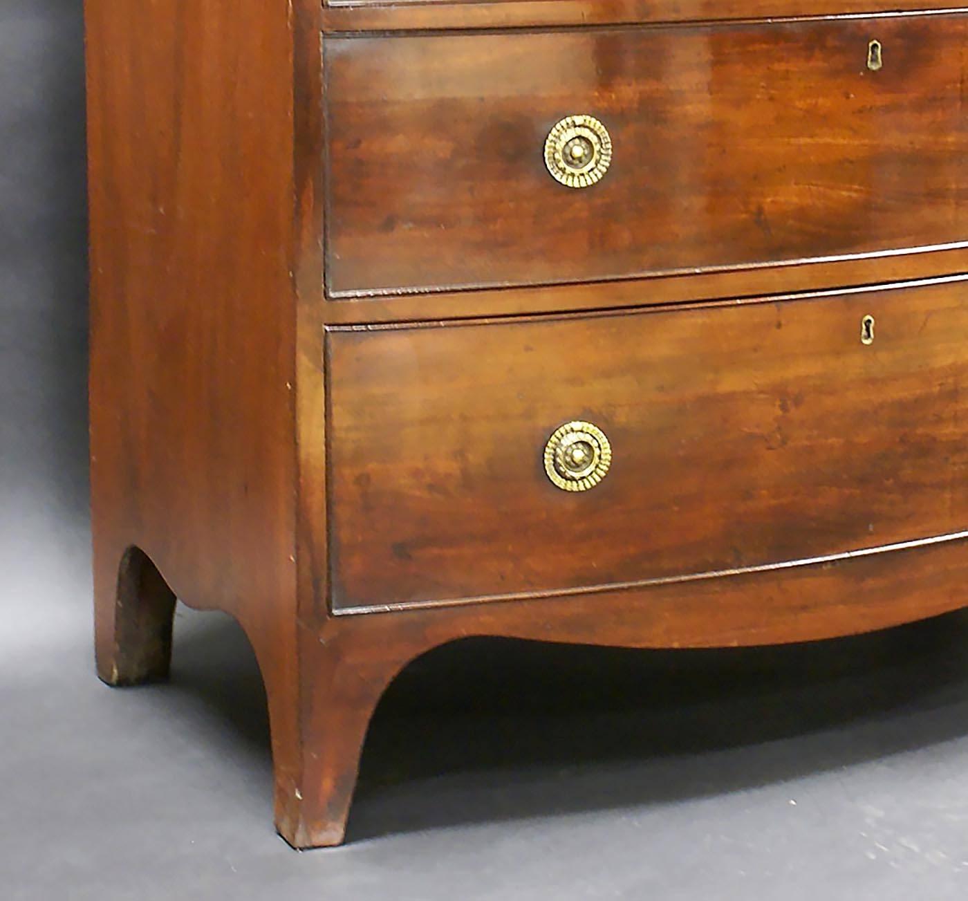 This handsome and excellent quality early 19th century, bow fronted mahogany chest of drawers features three long drawers with a brushing slide and brass ring drawer pulls. The chest measures 36 ¼ inches – 92 cm wide, 20 7/8 inches – 53 cm deep and