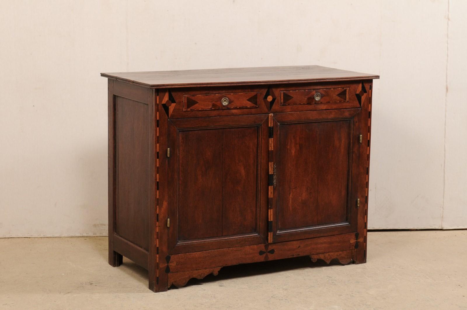 An English cabinet from the early 19th century. This antique buffet from England has a slightly overhanging top, over a base which houses two half-sized drawers at top, over a pair of doors beneath which open to reveal a shelf for additional storage