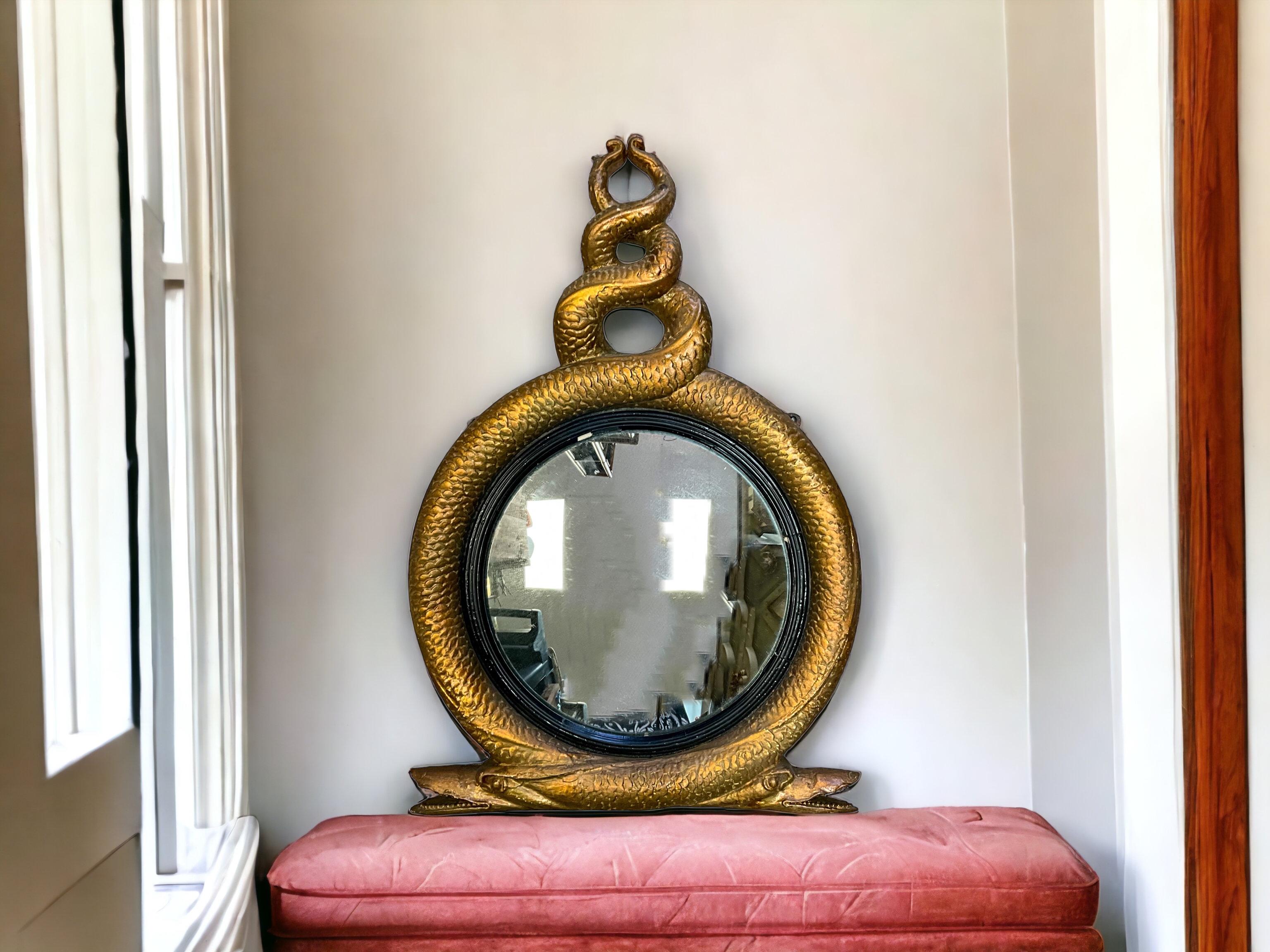 This is a show stopper. This is an early 19th century English Regency era gesso over giltwood convex mirror with intertwined eels. It has had restoration over time but is a really unique mirror. The glass is framed by ebonized wood. The mirror is in