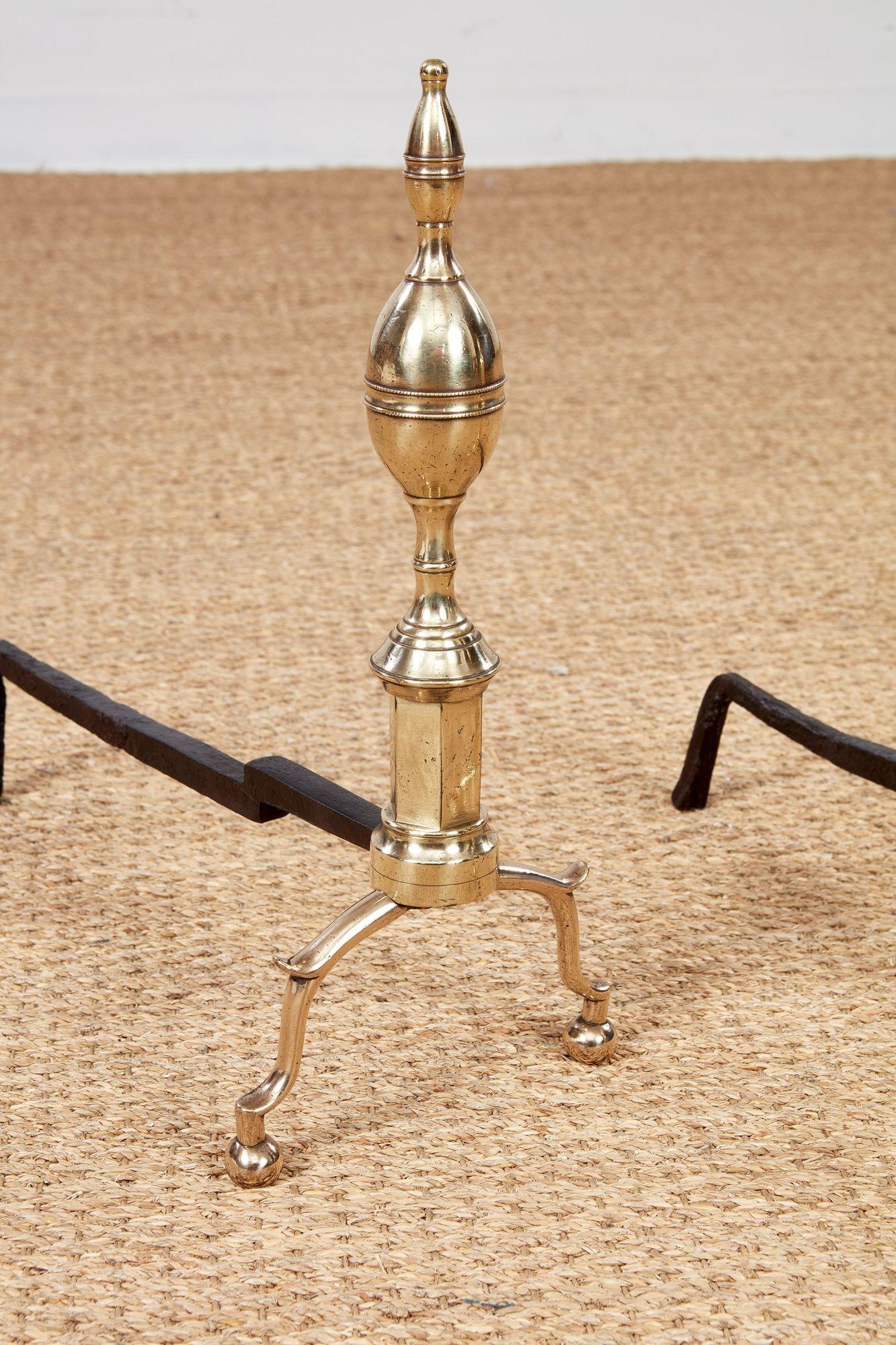 Fine pair of early 19th century American Federal period brass andirons with elongated spired lemon finials over having hexagonal shafts and standing on elegant arched spurred legs with ball feet.
