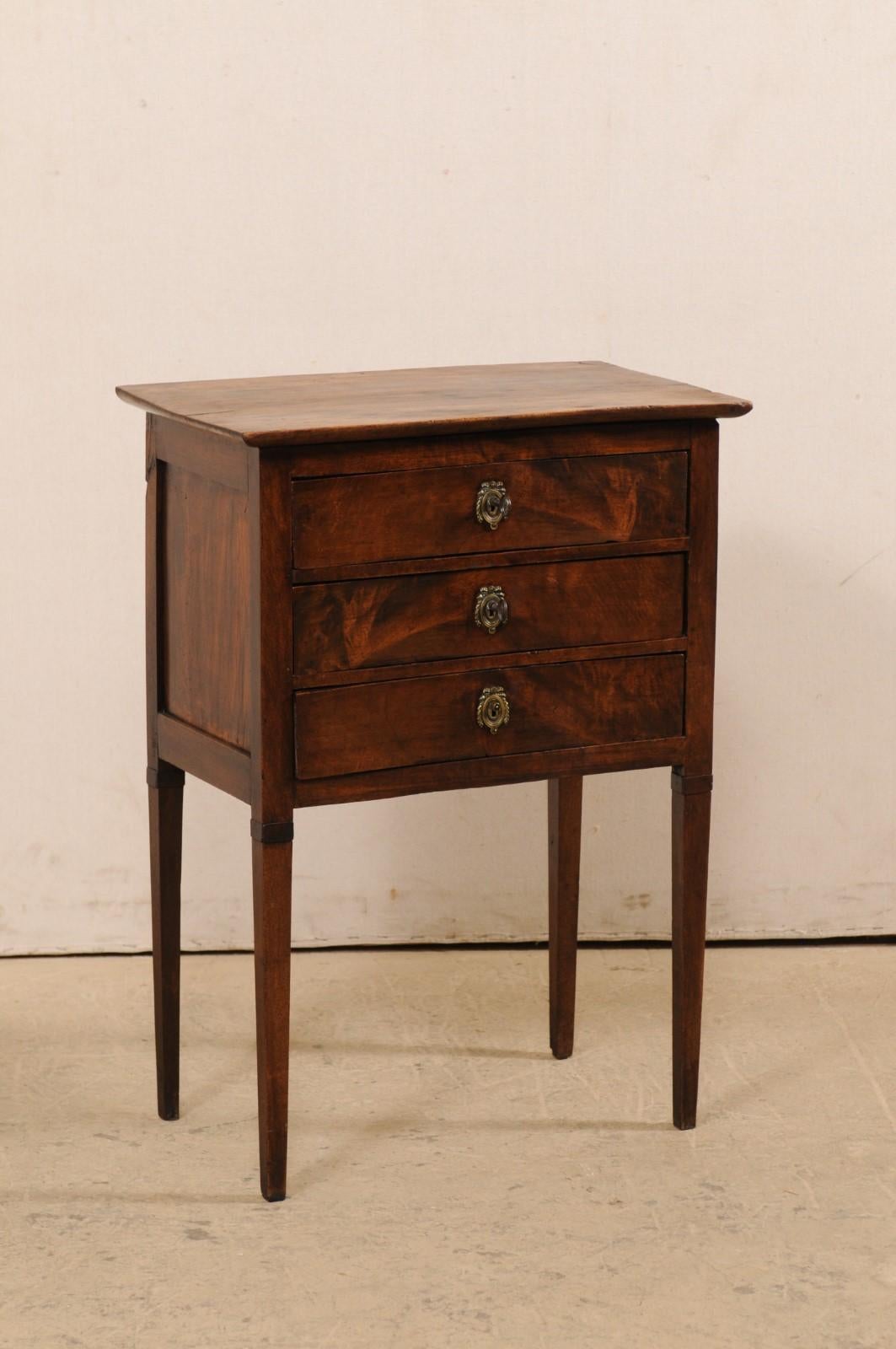 A French raised side chest with drawers from the early 19th century. This antique side chest or end-table from France features nice clean lines, allowing the beautiful wood grain to speak for the simple elegance of this piece. The chest houses three