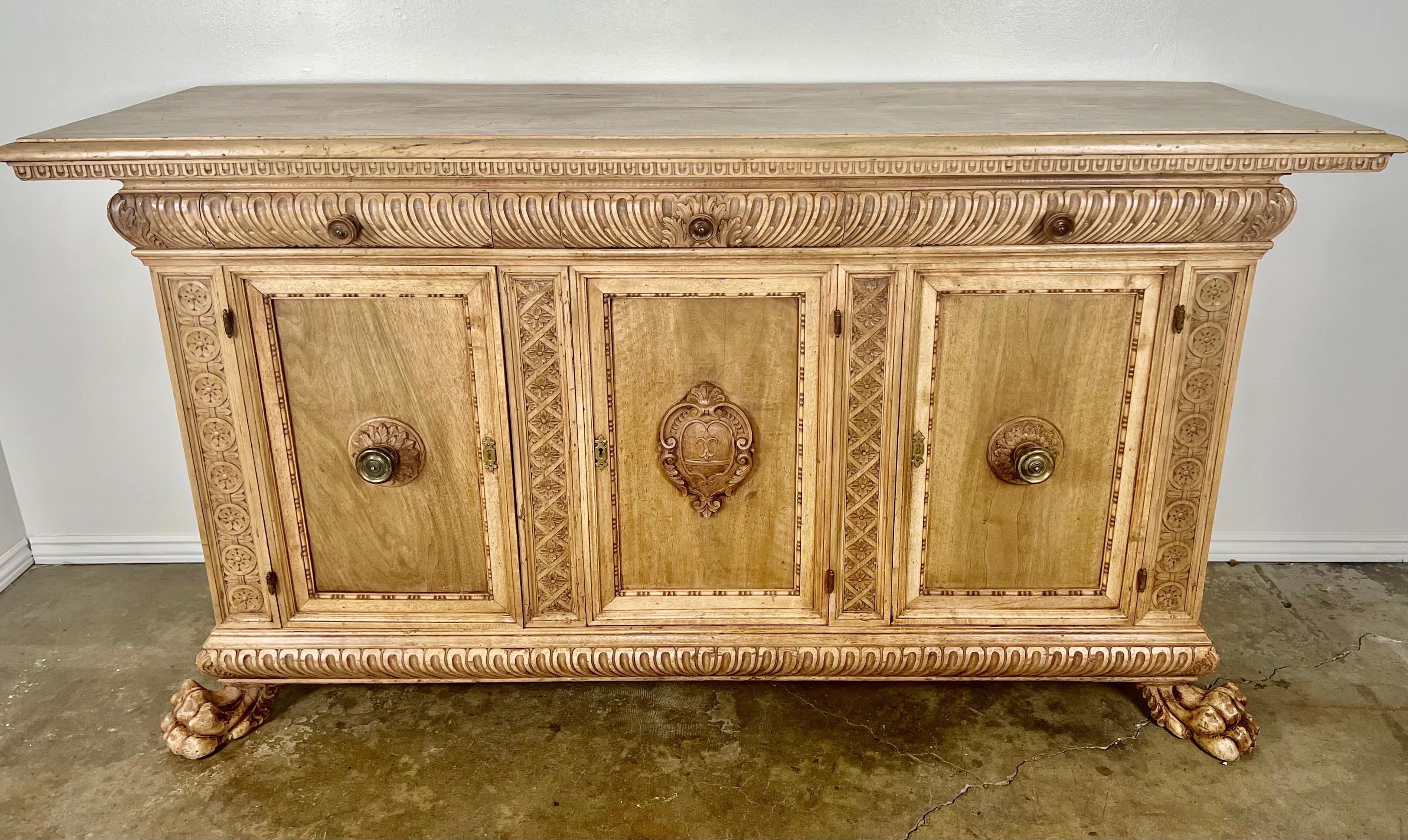 Early 19th century French Provincial carved credenza. The credenza has two working doors and three drawers for plenty of storage. The piece stands on two finely carved lion paw feet in the front. Notice the beautifully carved cartouche in the center