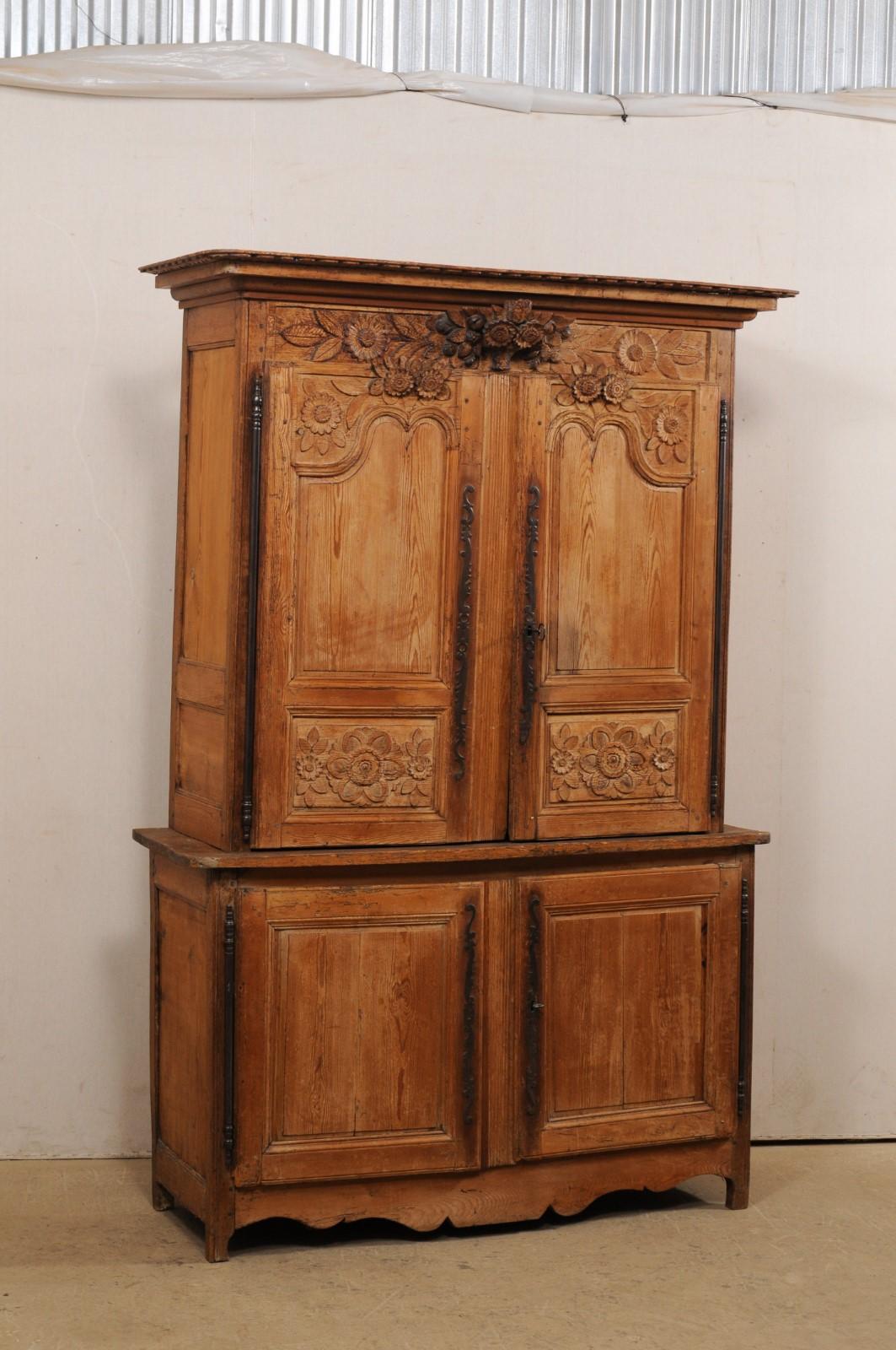A French tall carved-wood, four-door cabinet from the early 19th century. This antique cabinet from France, which stands approximately 7.25 ft tall, has been designed with a sweetly carved floral motif, which is emphasized with the three-dimensional