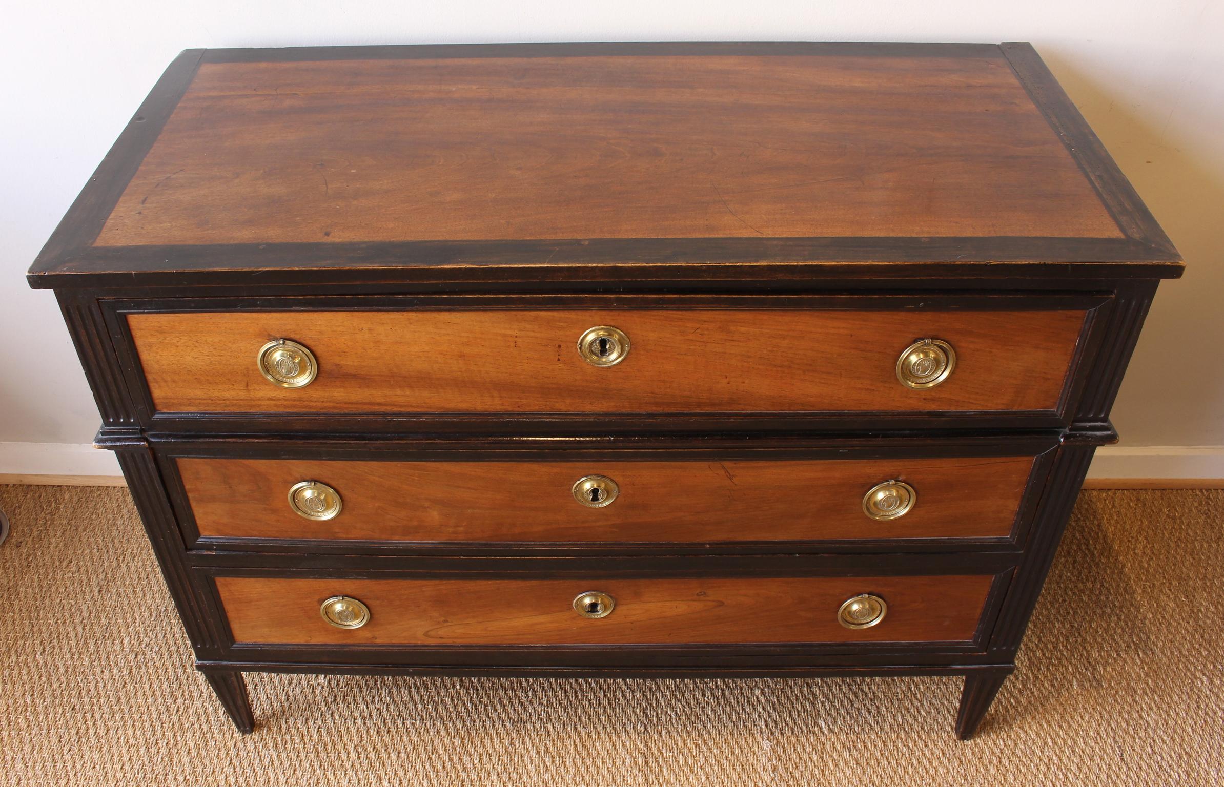 A large and impressive early 19th century French Directoire three drawer commode in ebony and fruitwood with original gilt brass pulls.