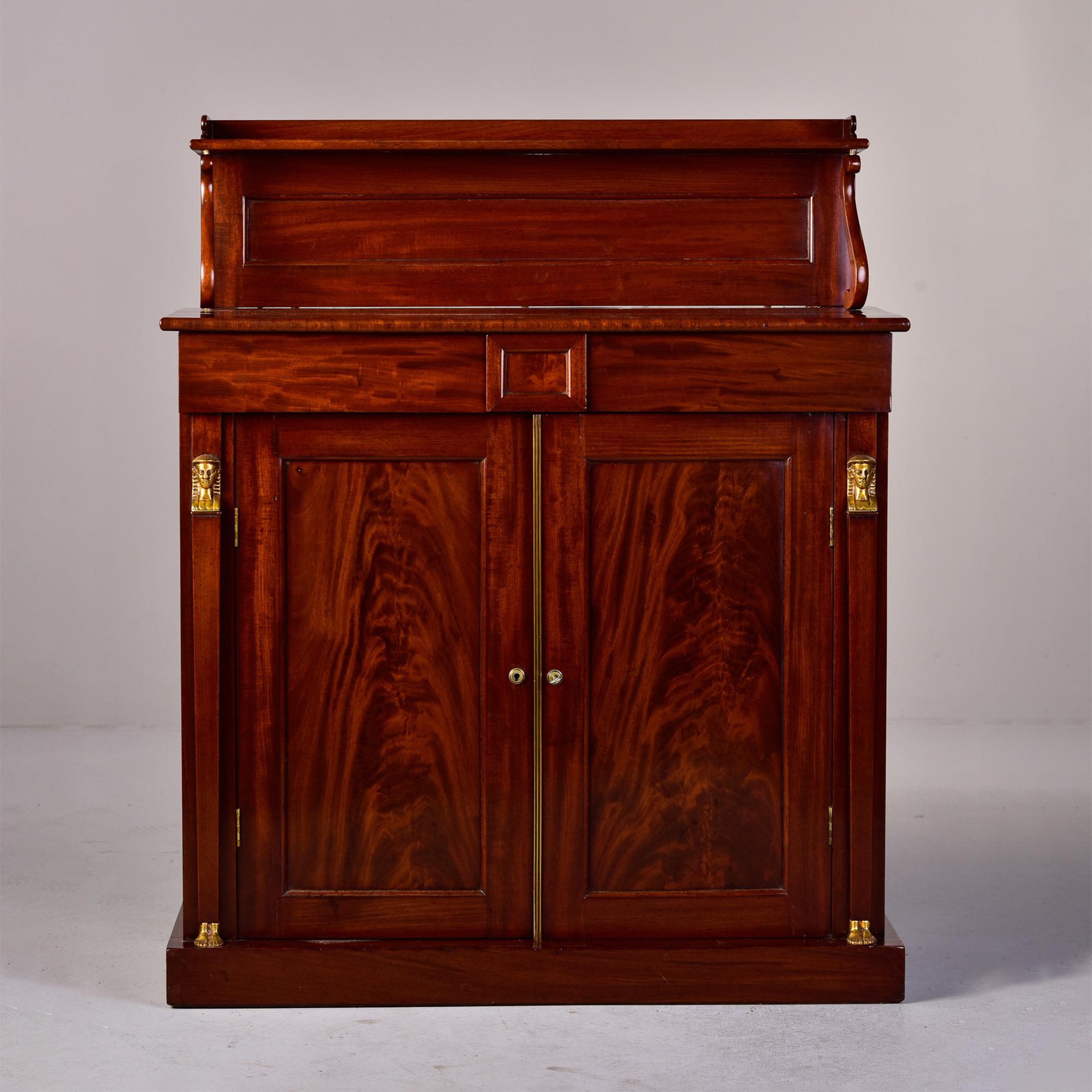 Circa 1815 French empire chiffonier made of mahogany with applied gilt bronze decorations with an Egyptian motif. Cabinet has lower hinged doors with functional lock and internal shelf on each side. Gilt bronze Egyptian bust and feet on sides and of