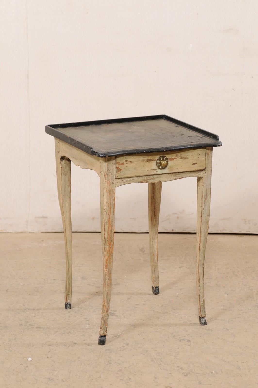A small French wooden side table with single drawer and leather top, from the early 19th century. This antique end table from France retains it's original black and green leather top, which is set within a raised lip along three sides. The apron