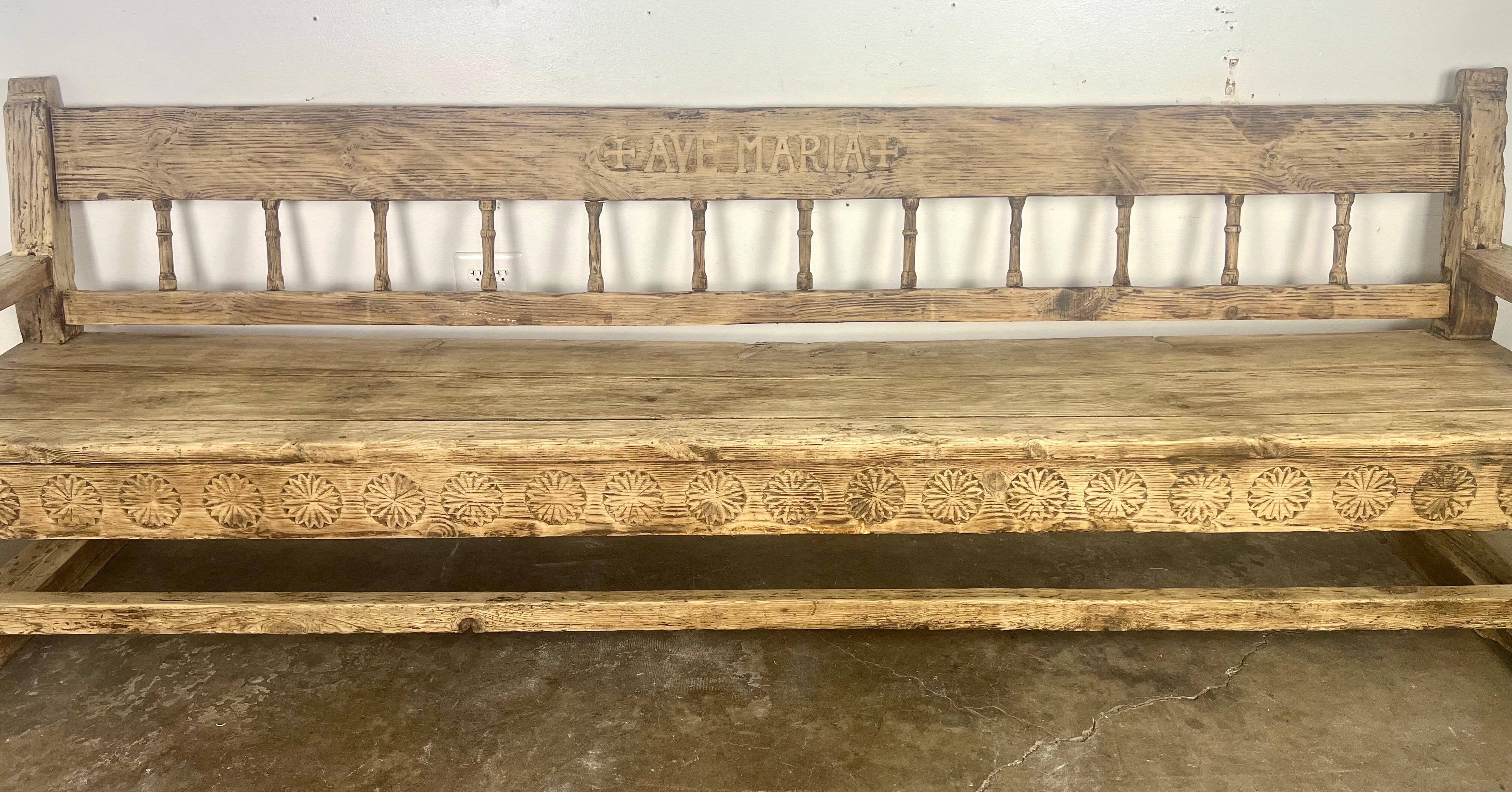 This rustic bench from the late 18th to early 19th century beautifully combines functional design with artistic craftsmanship.  The hand-carved rosettes on the apron add a decorative touch typical of the period, reflecting a fondness for floral
