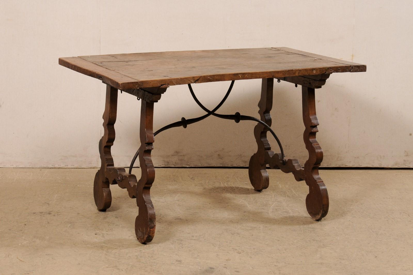 An Italian fratino walnut table with lyre legs and iron stretcher from the early 19th century. This antique table from Italy, in typical fratino style, features a walnut wood top, rectangular in shape, and raised upon a pair of lyre design inspired
