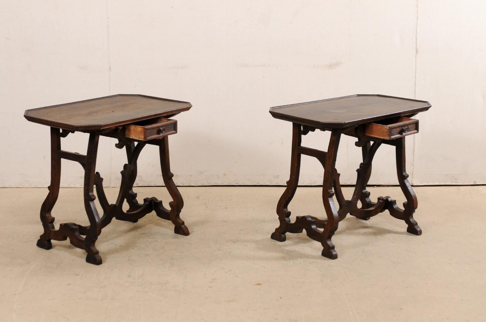 An Italian pair of carved walnut wood side tables, with single drawer, from the early 19th century. This pair of antique tables from Italy each feature mostly rectangular-shaped tops with four cut corners and slightly raised lip, with a single