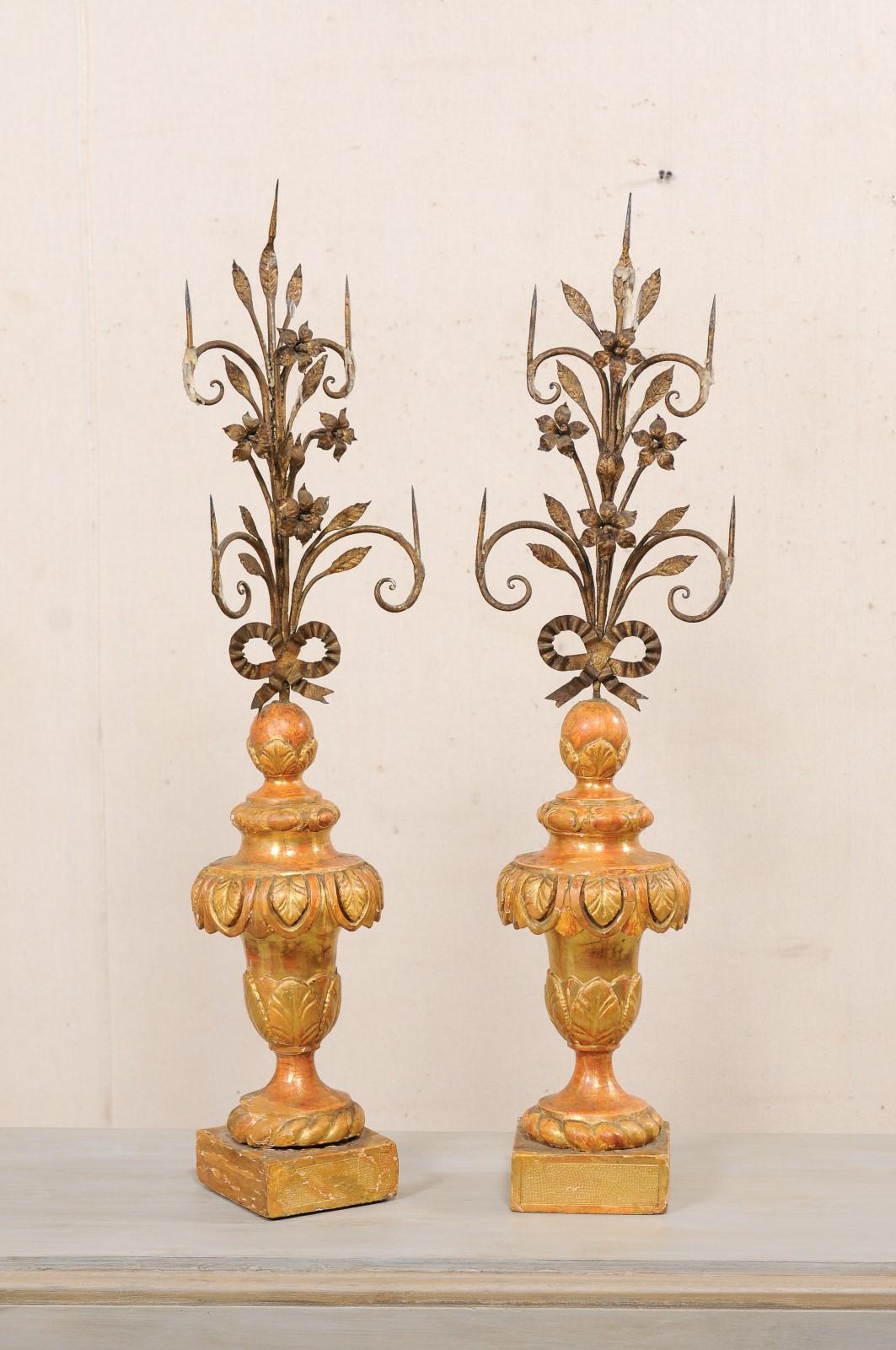An Italian pair of hand-forged floral iron prickets on carved wood bases, with their original painted finish, from the early 19th century. This antique large pair of prickets from Italy each feature beautiful forged and gilded iron shaped with