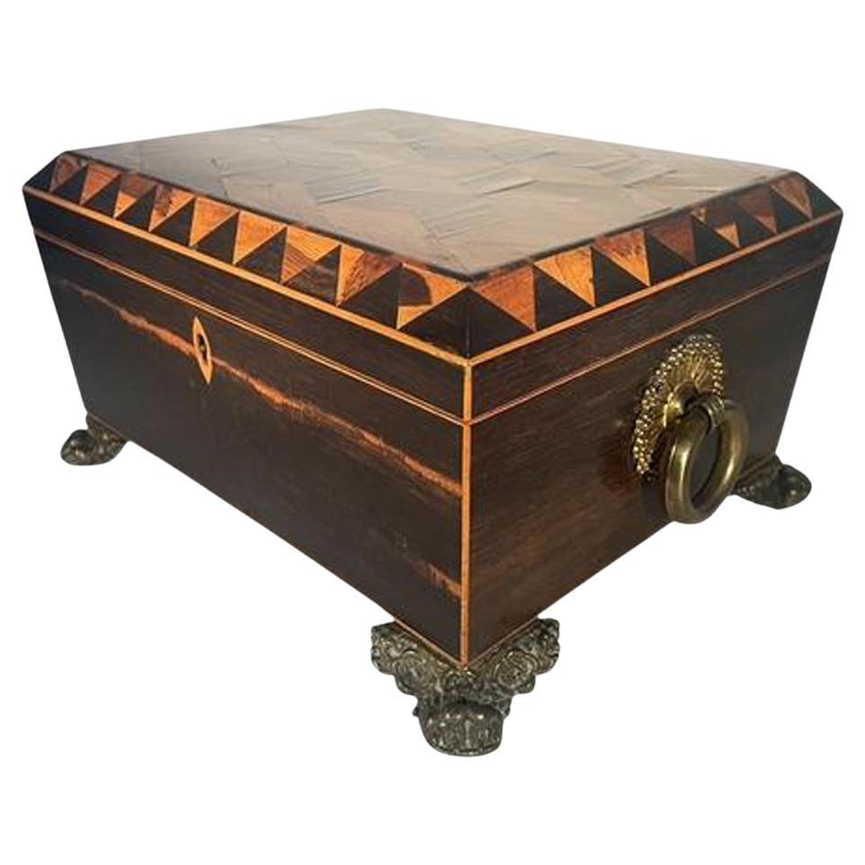 Regency period Tunbridge ware work or sewing box having calamander sides with light wood edges, the top with exotic woods inlaid in a tumbling block pattern within a Vandyke frieze border. The box with large brass ring handles and raised on brass
