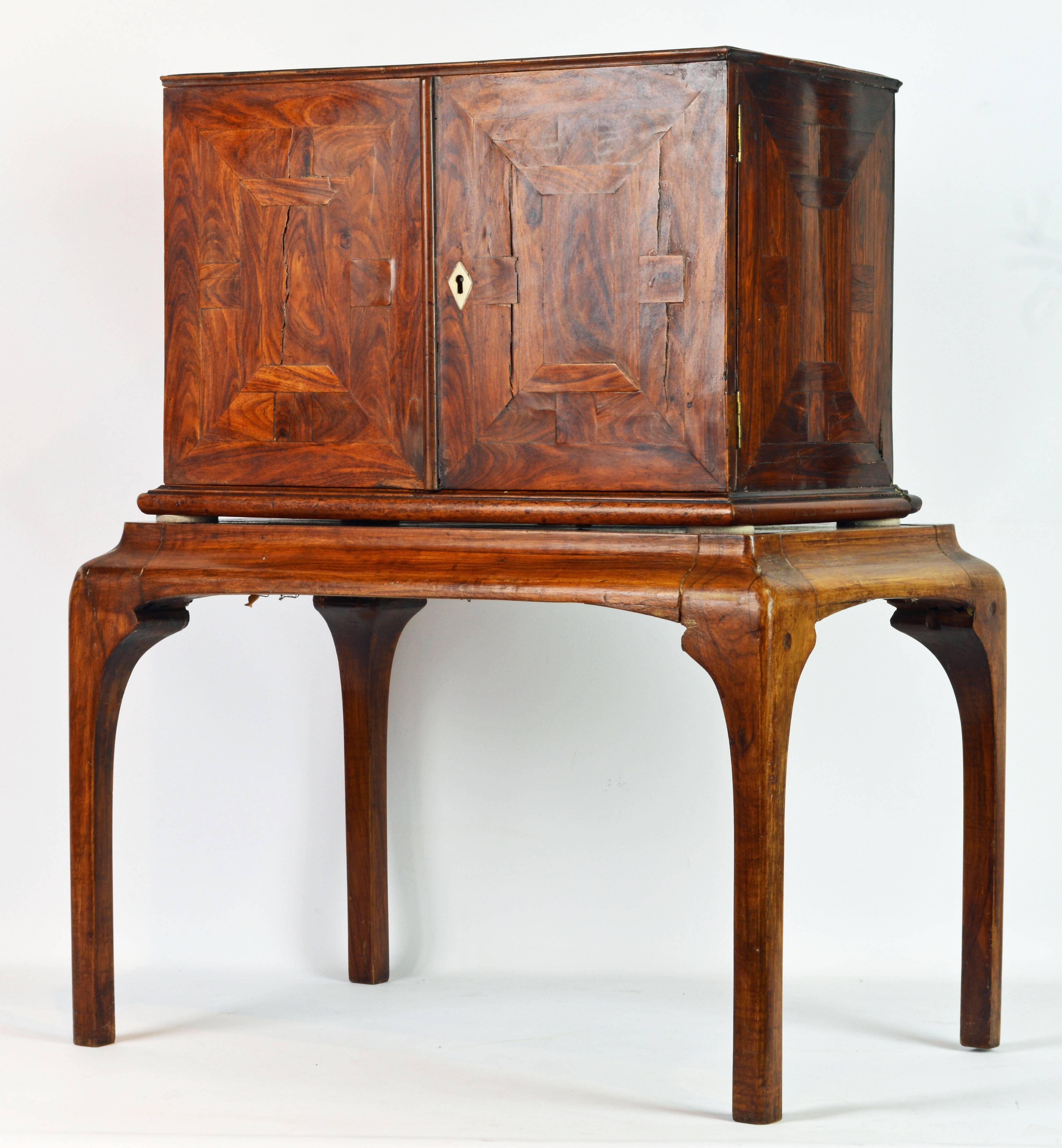 This unusual early 19th century Italian jewelry cabinet features a pair of parquetry doors (retaining original key) opening up to an interior fitted with nine small drawers (one of which with a secret compartment) and one long drawer with simulated