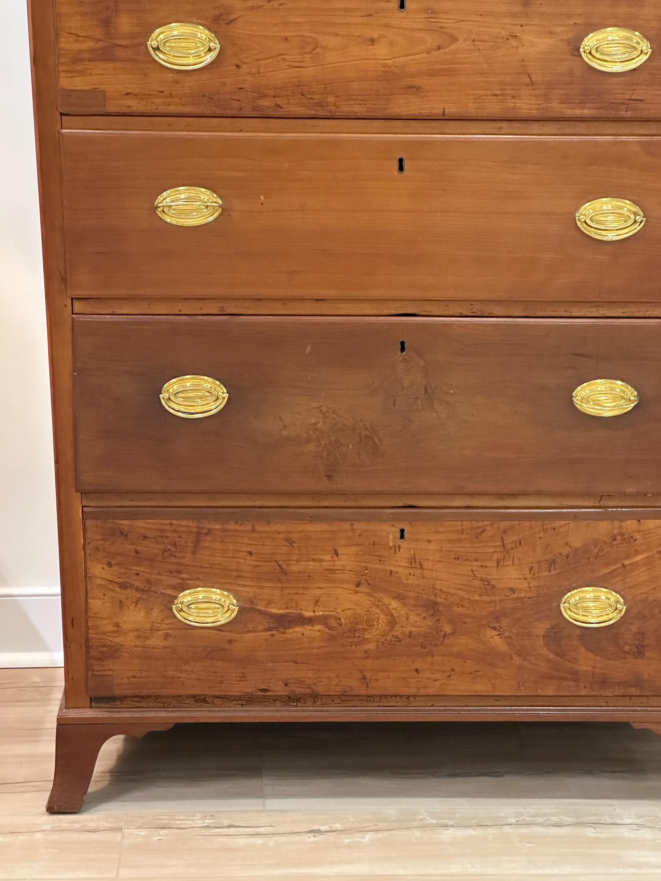 An early 19th C American cherrywood tall chest having three small top drawers with five graduated long drawers beneath all resting on splayed French feet.