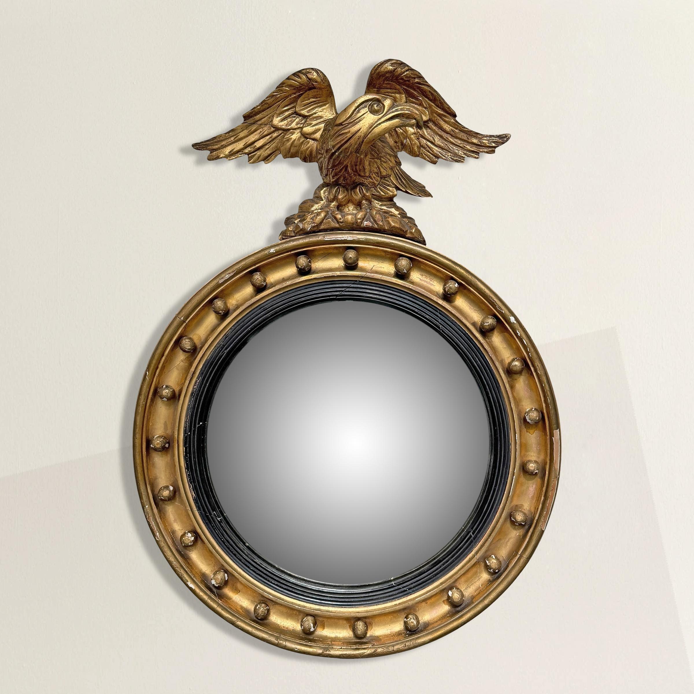 Few objects embody the drama of the Federal period quite like the bullseye mirror. This early 19th-century American example carries all the hallmarks: a convex mirror at its center, still original, encircled by a gilt frame studded with 23 perfectly