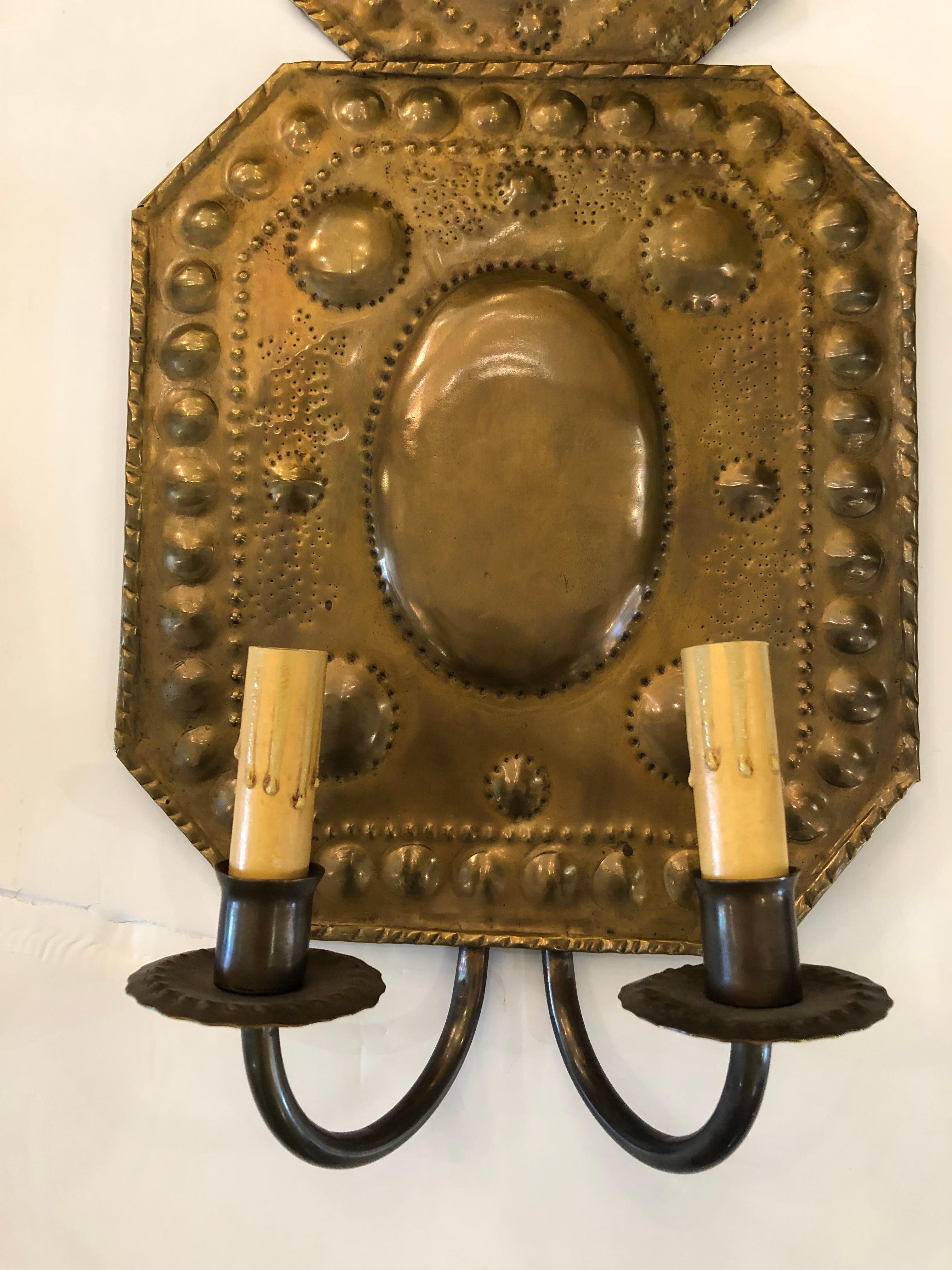 Charming pair of hammered brass 19th century wall sconces having a folk art feel with hearts at the top and octagonal sections with circles and oval decoration. Fully electrified with two arms per sconce.