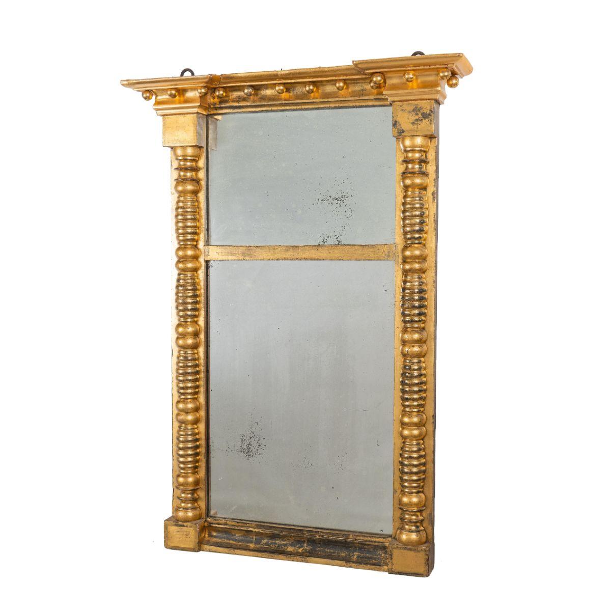 American Sheraton split pillar, gilt gesso, two part tabernacle looking glass with a projecting blocked cove cut cornice, fitted with 12 gilt balls. The frame retains its original gilt surface and mercury amalgam mirror.
American, New England,