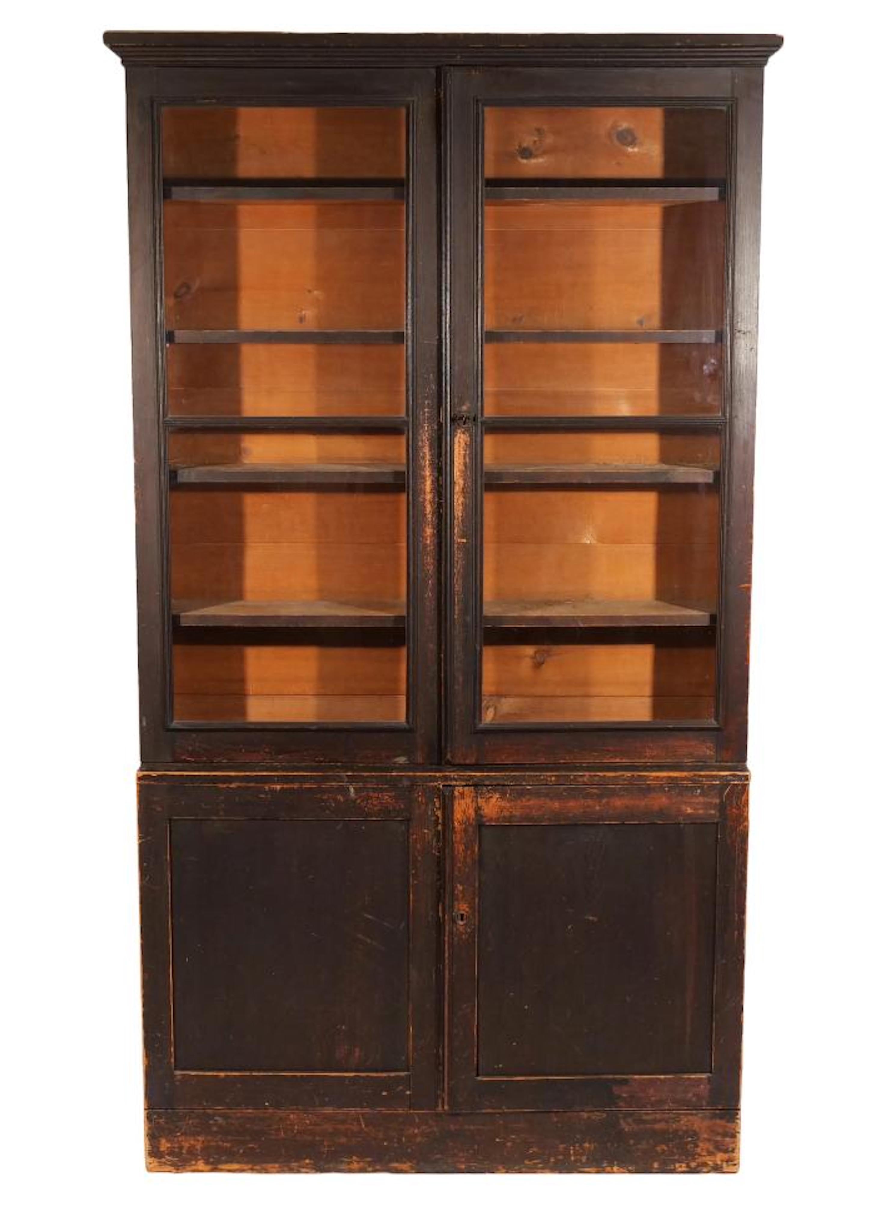 An early American painted bookcase of nice shallow dimension.  From either New York or New England, of step back-form with a molded cornice over double glazed doors, over double cabinet doors.  One piece construction.  The cabinet is painted an old