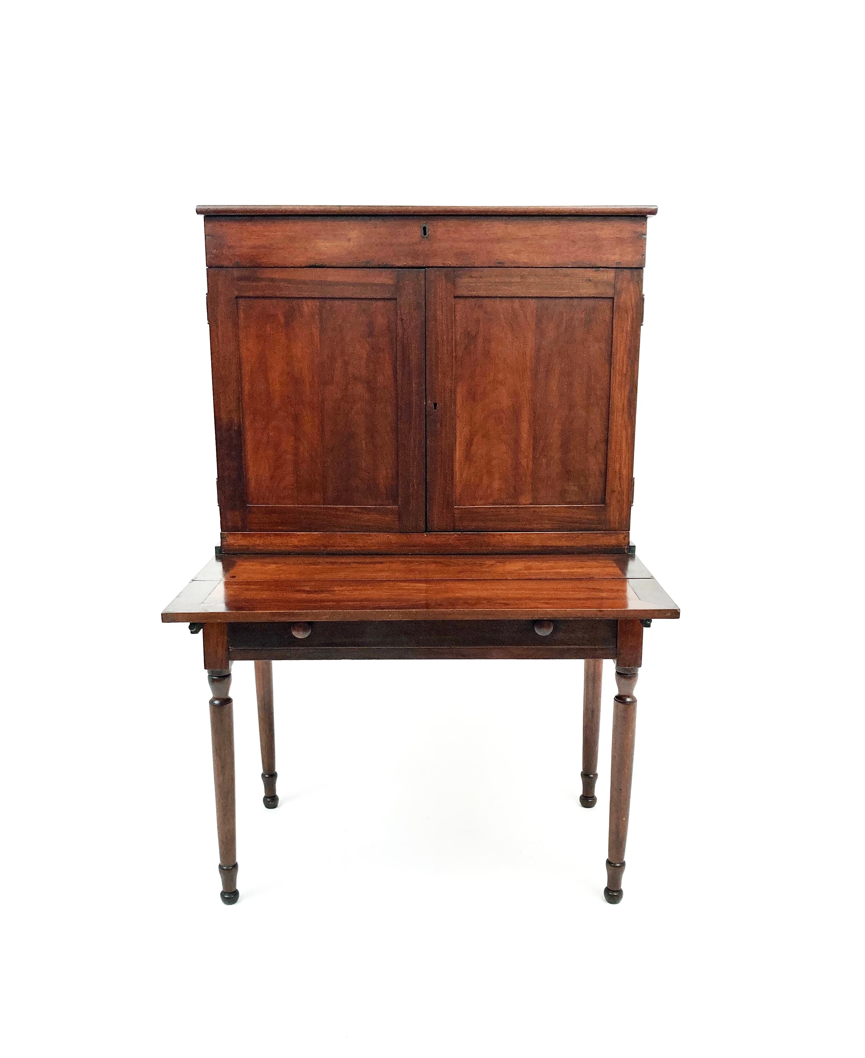 Circa 1830's, this walnut Federal Sheraton style plantation desk has a single front drawer on the lower desk and double doors on the upper piece. The double doors open to reveal intricate nooks and a drawer for storage. There is a hidden storage