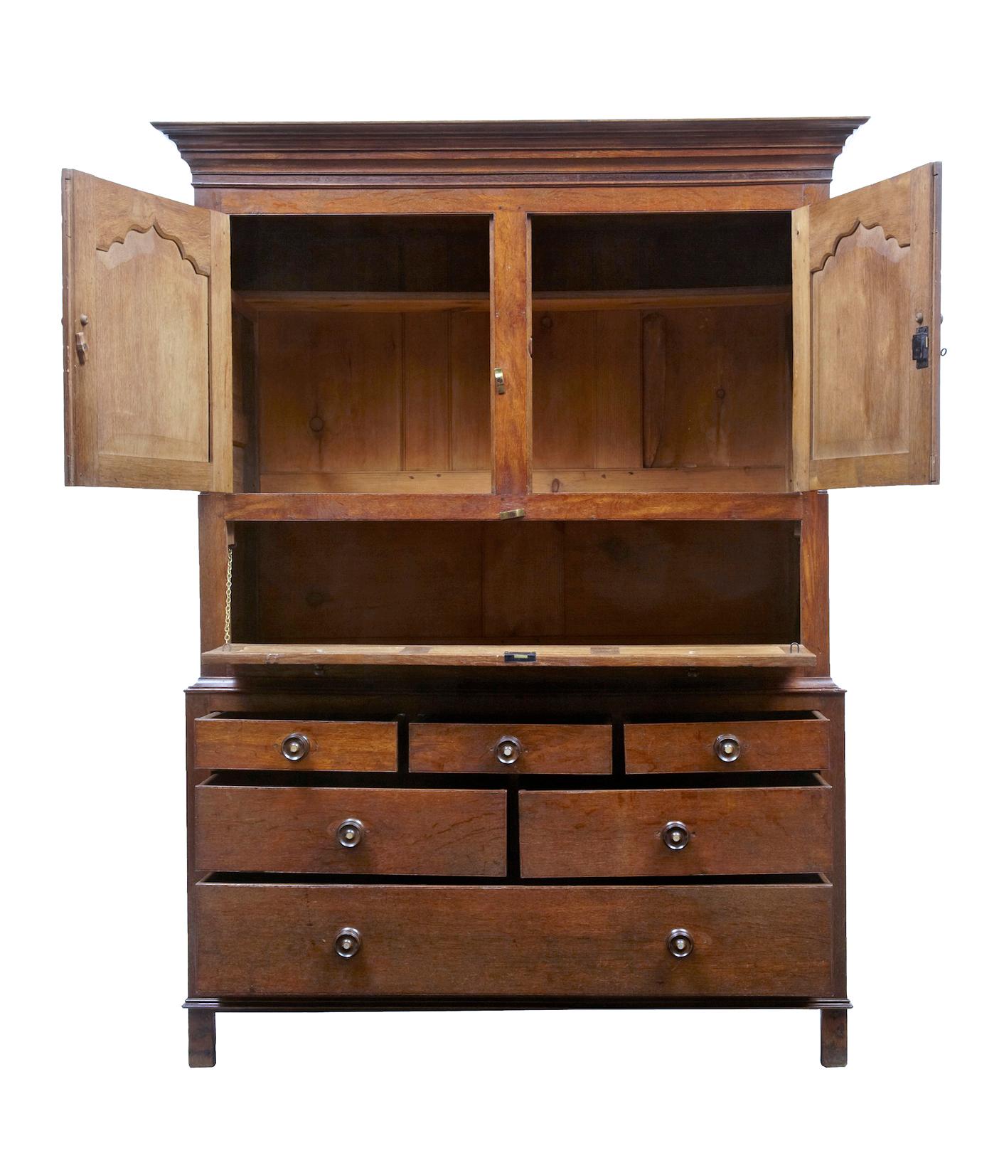 Good quality oak cupboard. Splits in two parts, top section comprising of double oak doors which open out to reveal small shelf, underneath a drop down hatch door with further cupboard space. Bottom section consists of three short drawers over two