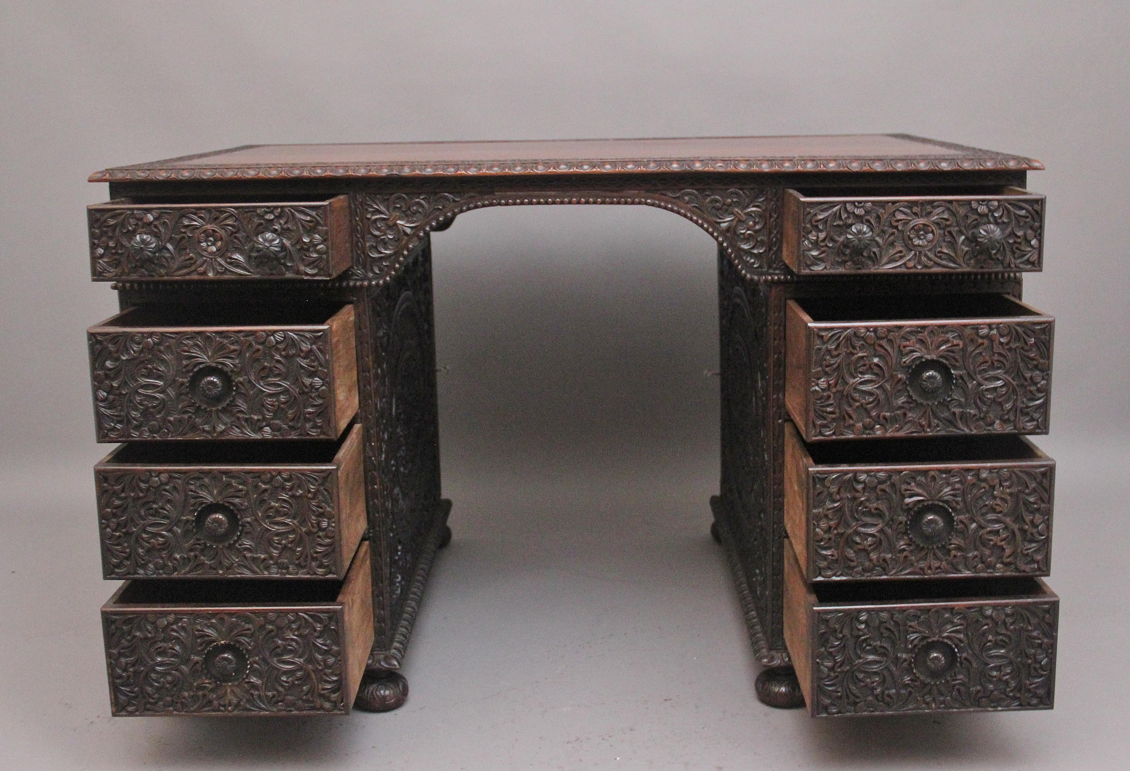 A lovely quality early 19th Century Anglo-Indian carved padauk partners desk, having a nice figured top with an ornate carved border and gadrooned edge, a selection of eight graduated drawers below with the original carved wooden knob handles and
