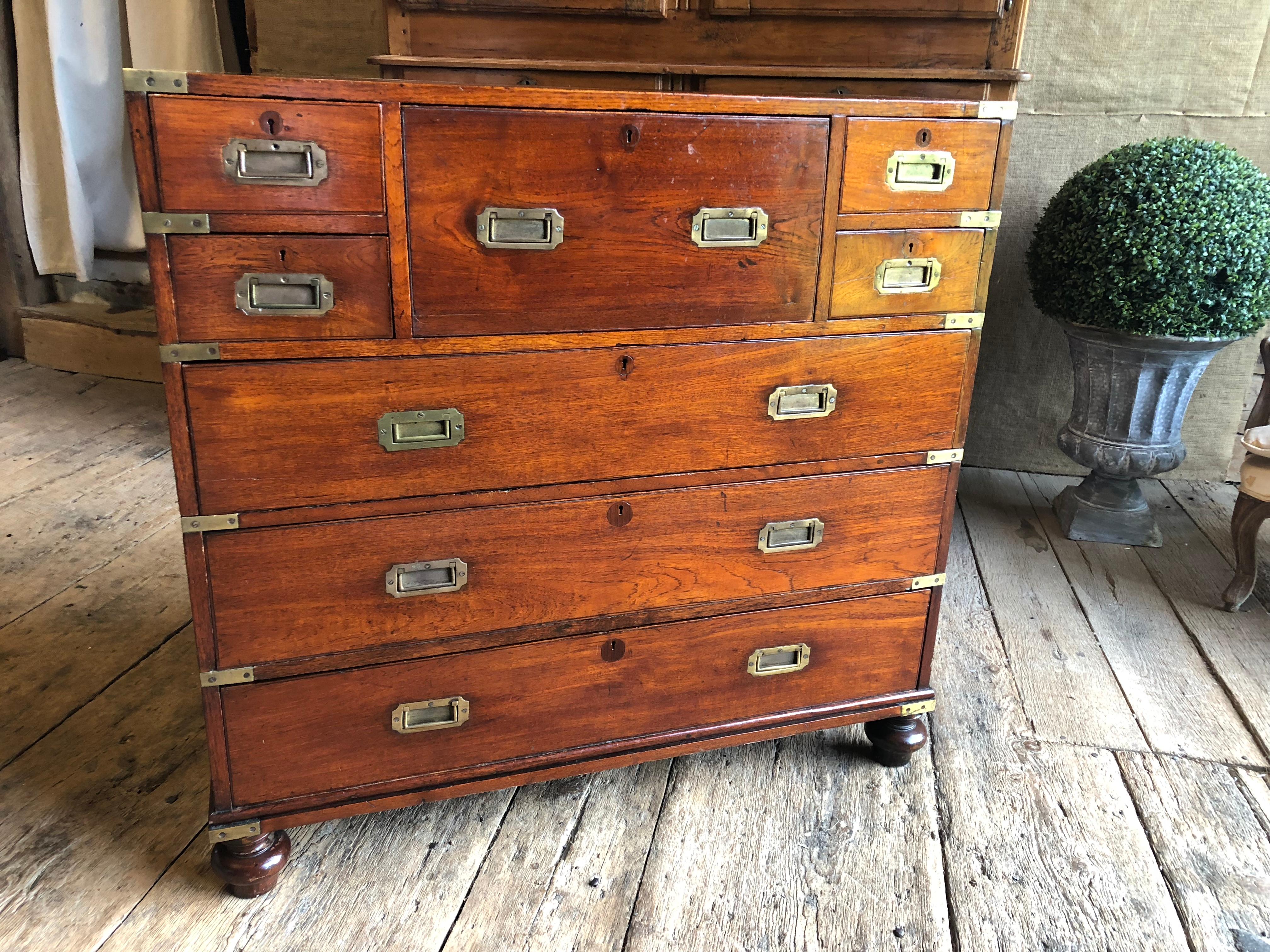 An early 19th century Anglo-Indian campaign chest in two parts with drop-front desk, in mahogany with brass hardware marked with a maker’s stamp and “Calcutta”, all on turned feet.
Campaign chests were brought by British military officers on their