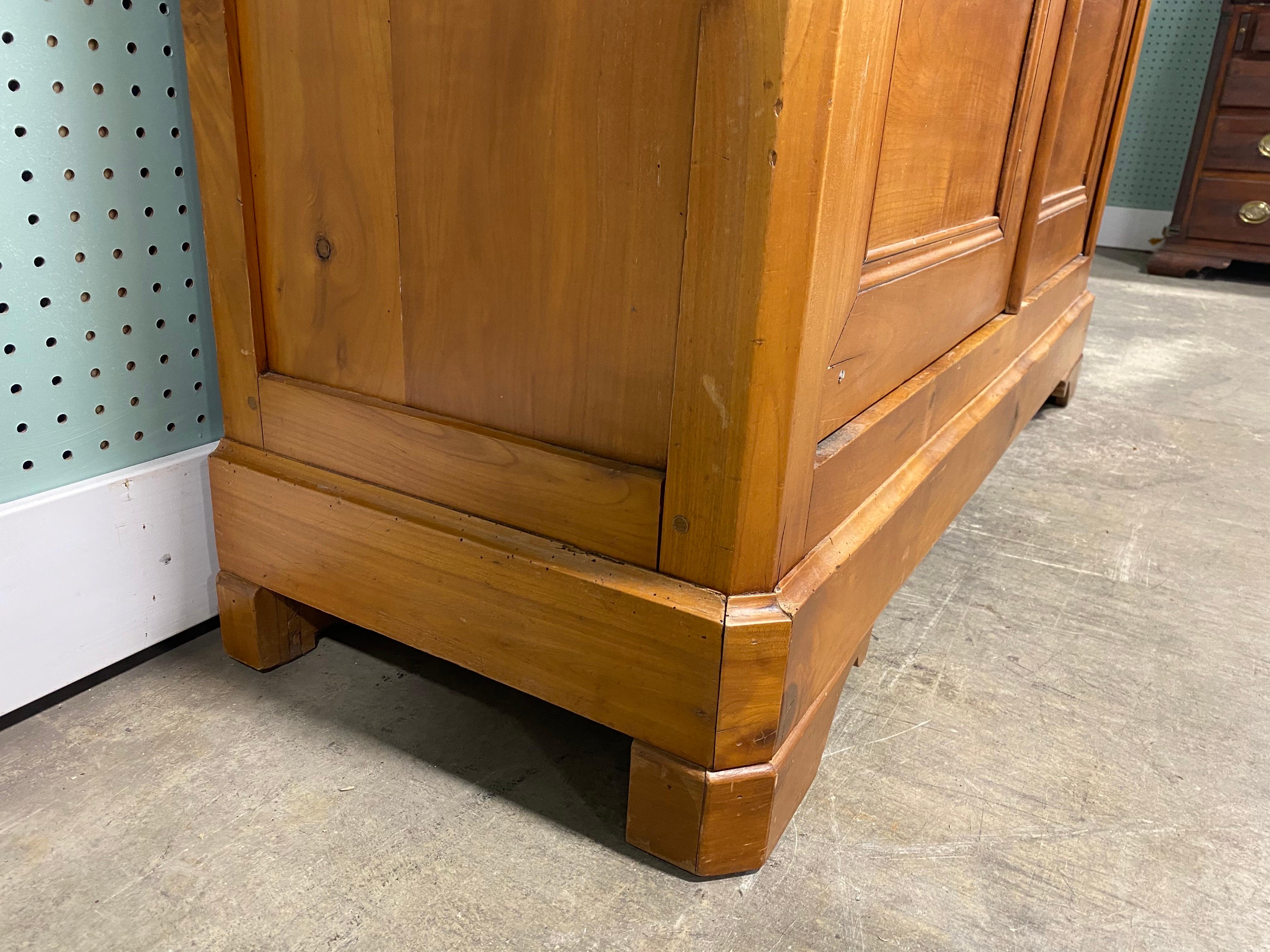 This is an early 19th century handmade French country Cherrywood cabinet/bookcase. This cabinet has a beautiful amber patina to the Cherrywood and features as original pewter hardware. The cabinet has beautiful scrolled Empire style feet and the