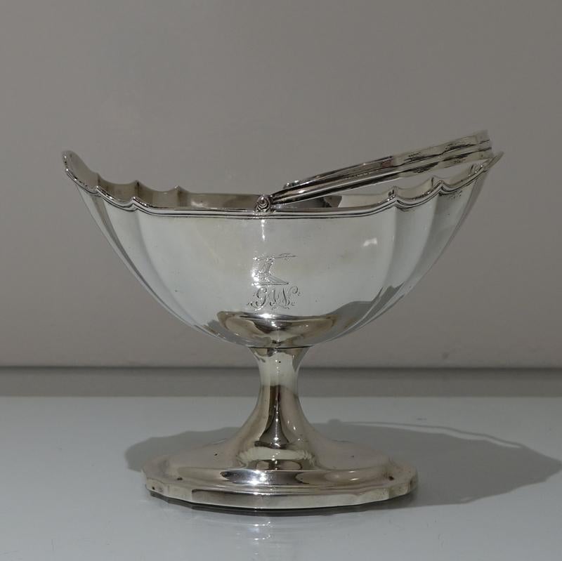 A beautiful plain formed fluted Irish swing handled sugar basket. The raised pedestal foot is also plain formed to elegantly complement the body. The centre front has a contemporary crest with entwined initials for importance.

Weight: 9.7 troy