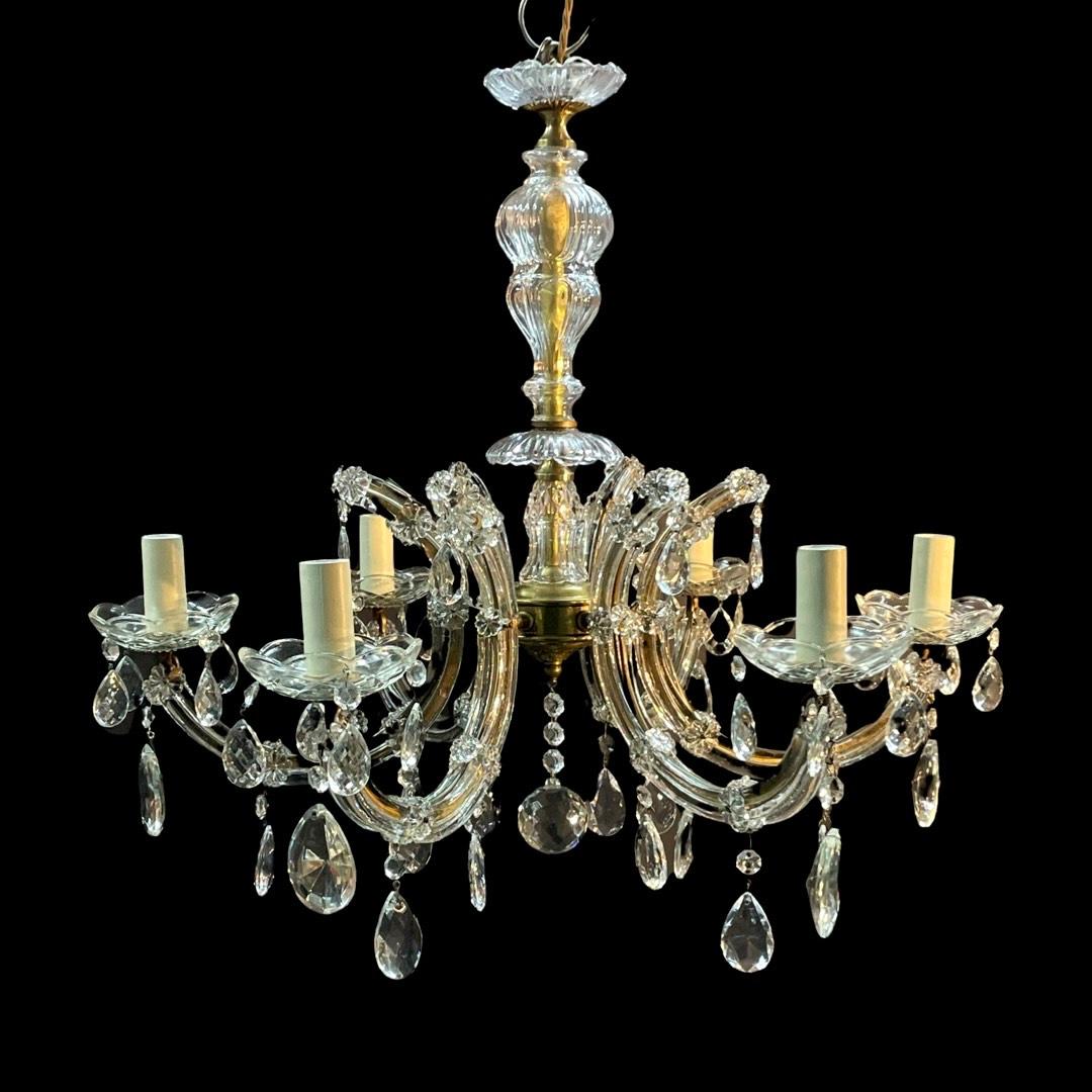 Experience the timeless elegance of a stunning Maria Theresa 6-arm chandelier from the early 19th century.



Crafted with flat brass arms finished in golden hues, each adorned with exquisite crystal strips and rosettes, these chandeliers radiate