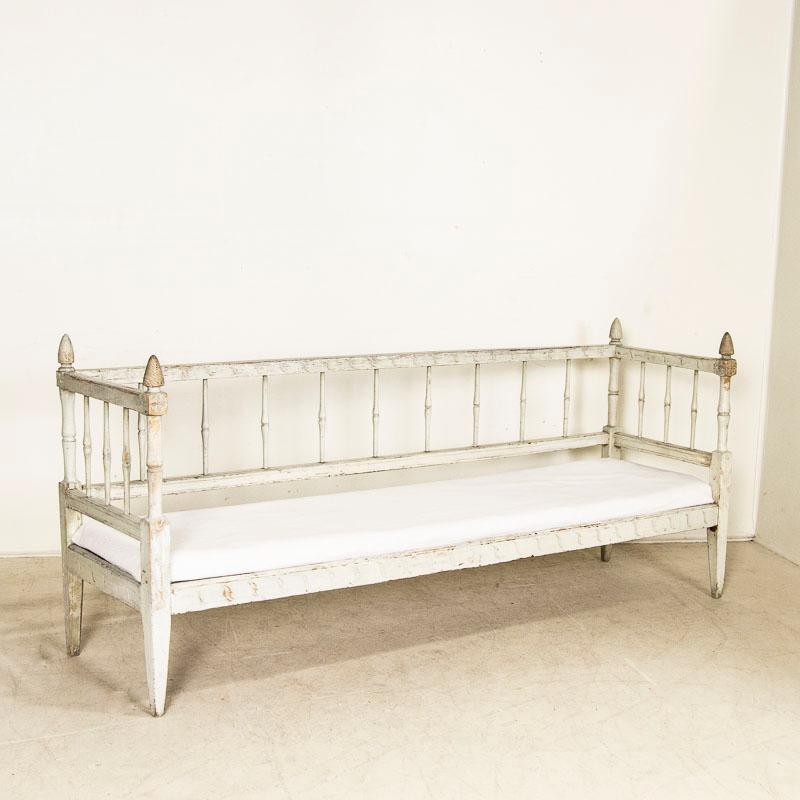 This lovely long bench is a wonderful example of Swedish Gustavian craftsmanship with delicately carved details including a branch and leaf design. Carved finials and tapered legs add to the timeless appeal and style. The original light dove gray