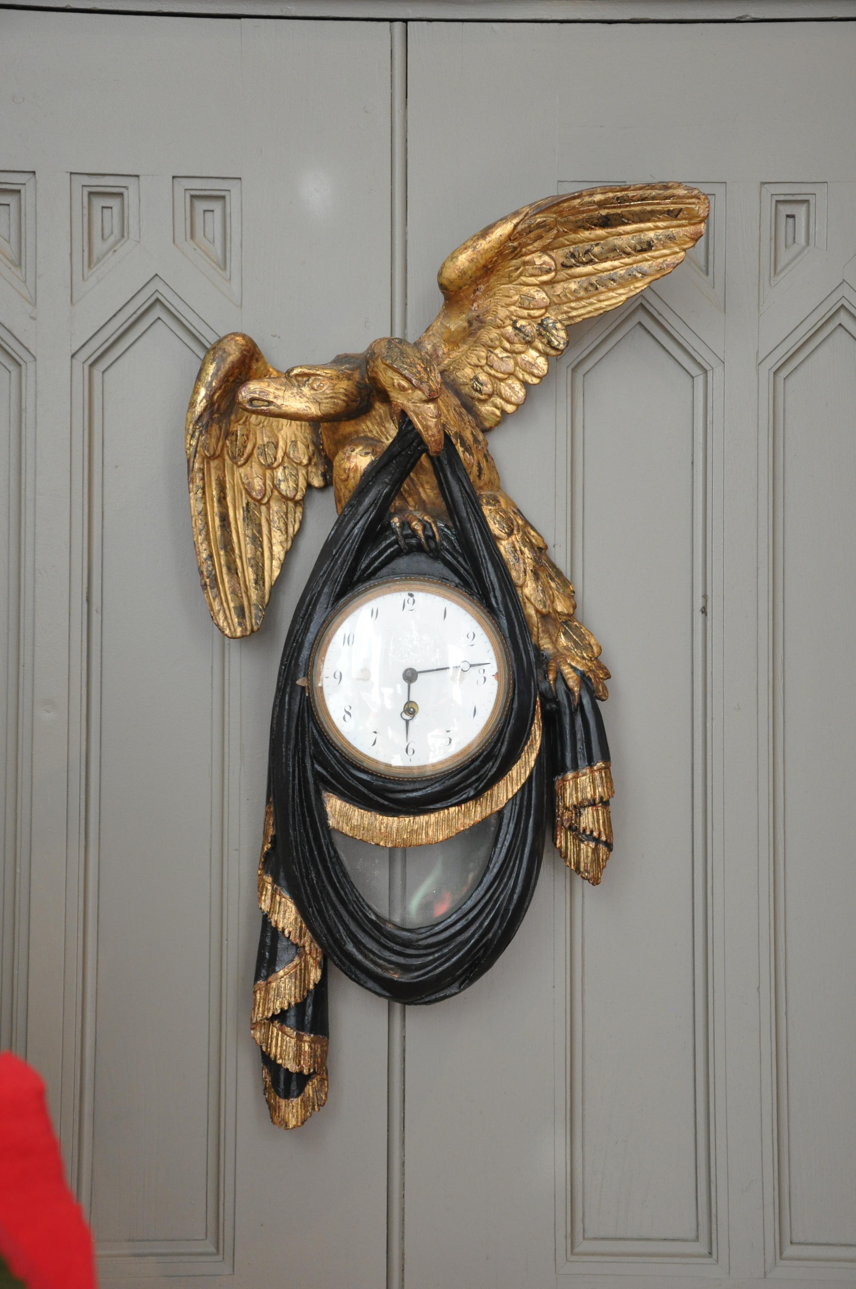 Rare form of a double-headed Hapsburg Eagle wall clock. Early 19th century with a chic black painted swag. Can always be fitted with a modern clock work. Dial and gilding original