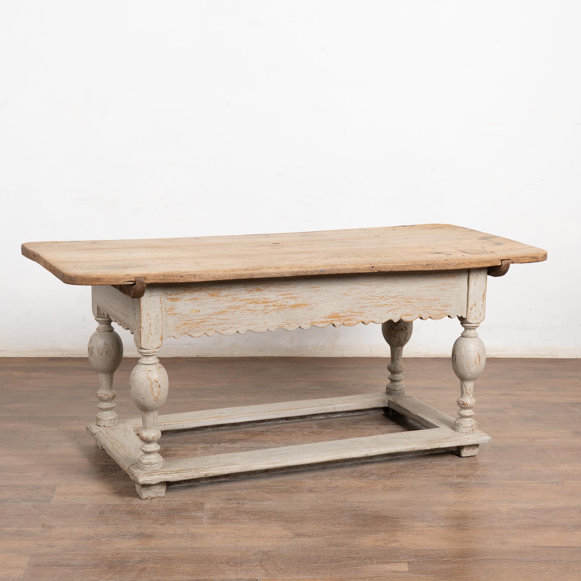 This handsome oak work or refectory table in the Baroque style is from Denmark. The natural oak plank top shows age-related separations, old patches/repair, and stains from long use all adding to its rich, aged character. The base has been given a