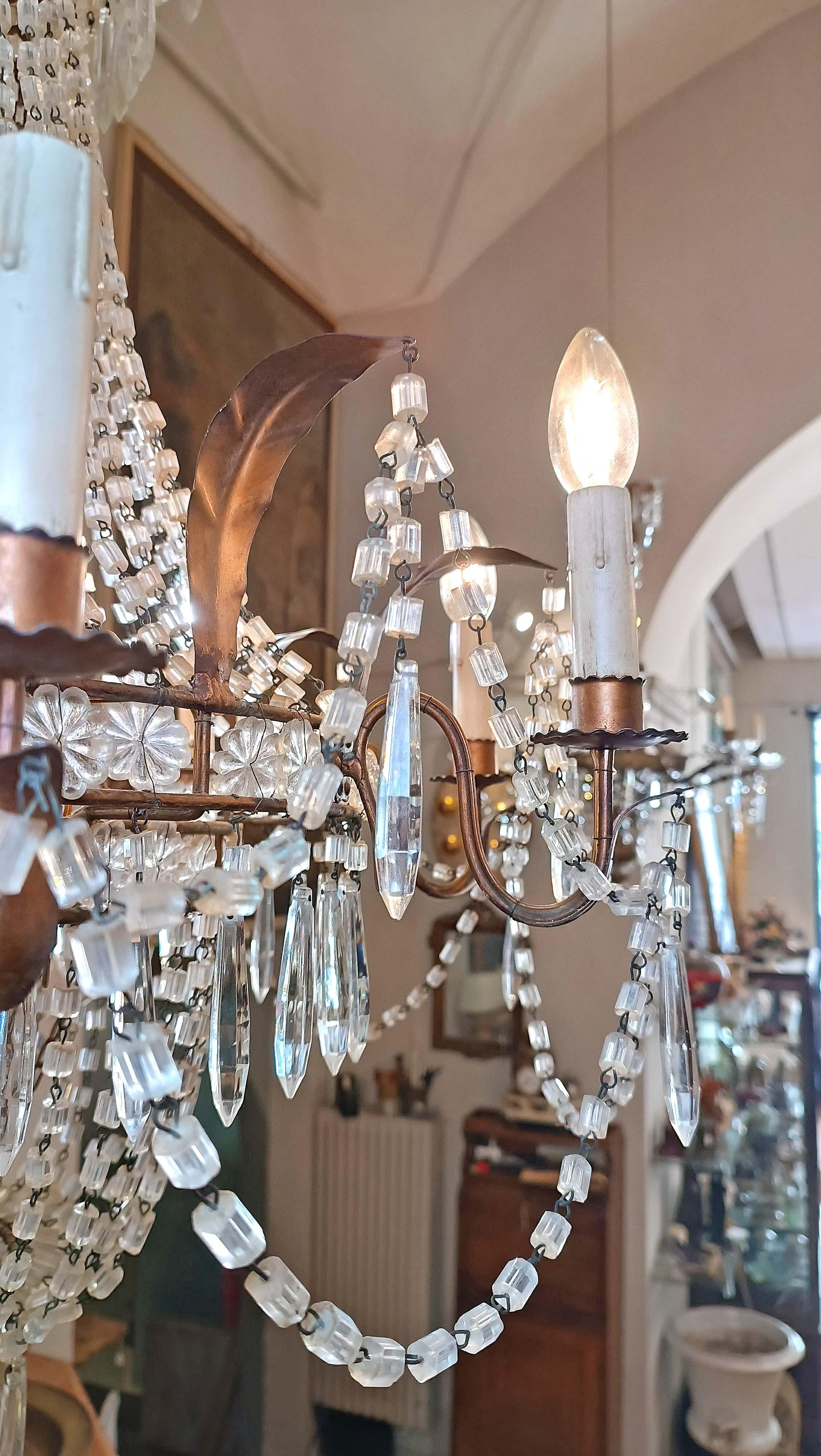 Elegant basket chandelier in crystals and gilded iron, with eight lights. The structure is made of iron, embellished with leaf decorations also in gilded iron, which enhance its overall appearance. The crystals, characterized by chains and pendants,