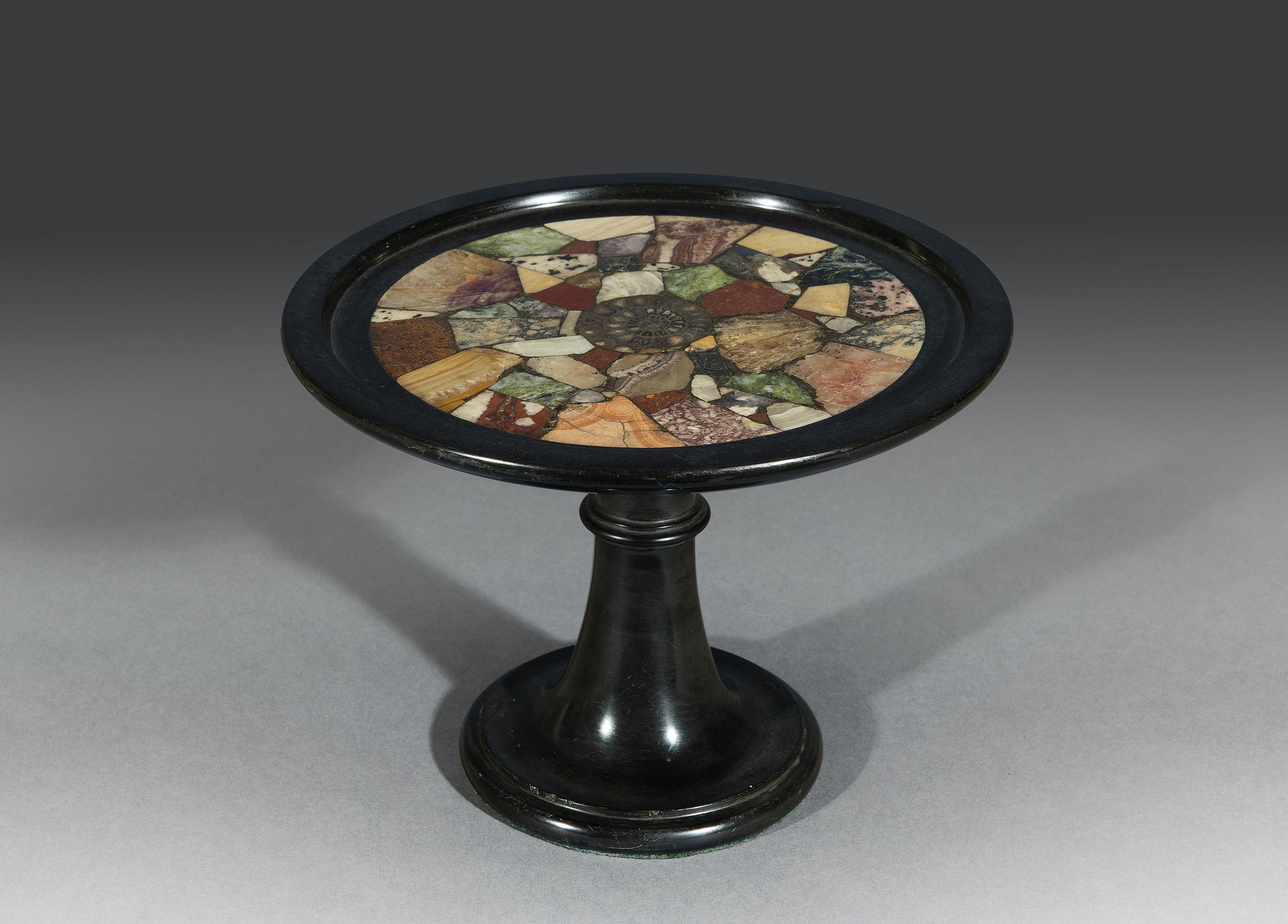 The shallow Belgian granite dish is inlaid with various marble specimens that surround an Ammonite fossil. The dish sits on a ring turned column and socle. 

N.B. 

Belgian Granite comes from the area of Soignies in Belgium and its appearance is