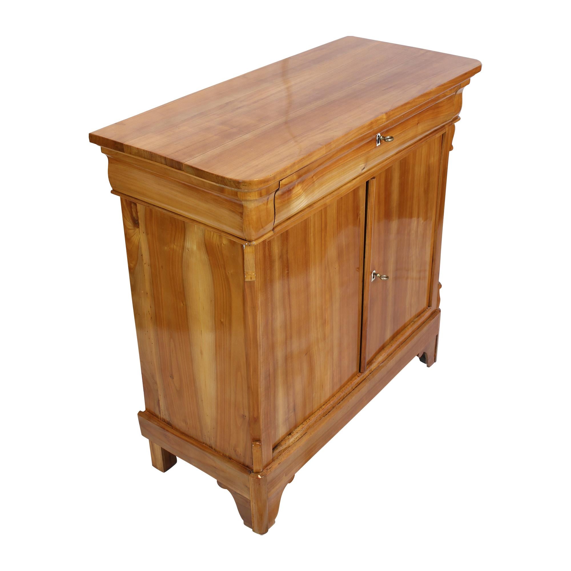 Beautiful and practical Biedermeier half cabinet made of solid cherry wood. The cabinet has a drawer at the top and 2 opening doors at the bottom. A brilliant piece of Biedermeier in very good quality.