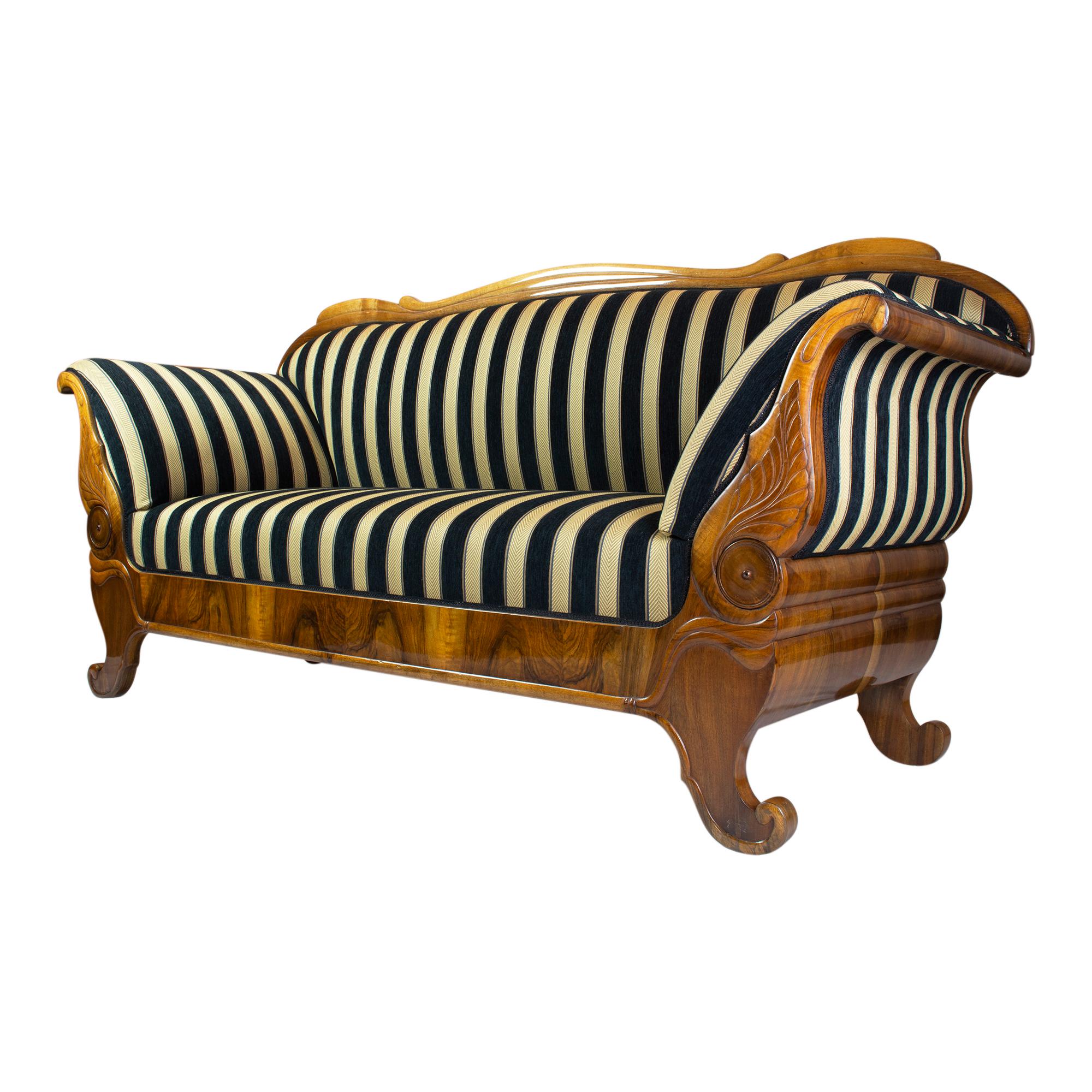 The Biedermeier sofa, dating back to around 1825, is a true classic piece of furniture. Made from beautiful walnut wood, it has been hand polished with shellac to achieve a stunning finish. Recently reupholstered with new Biedermeier fabric, it