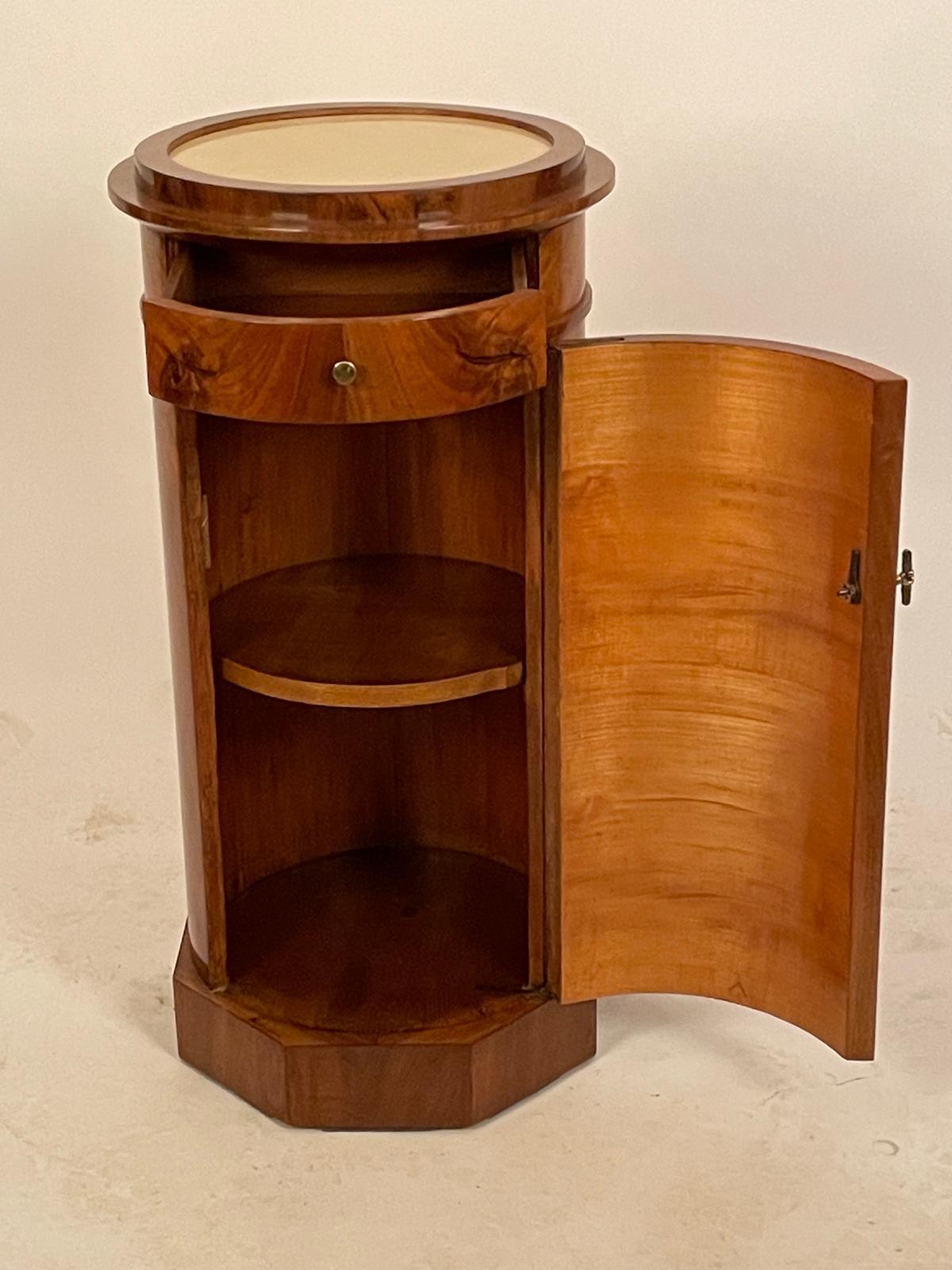 Nogal y pizarra de Solnhofen (Austria) 
Viena, hacia 1820 
Altura 84 cm, anchura 39 cm, profundidad 39 cm  
Mesilla de noche o armario en forma de columna de nogal con tapa circular de pizarra de Solnhofen. La pieza tiene una estructura cilíndrica