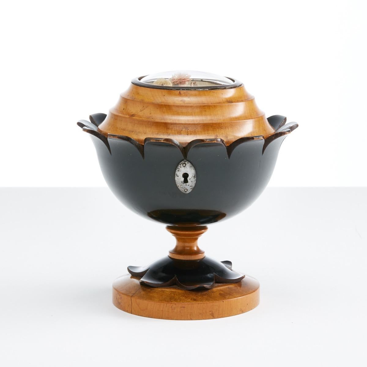 This caddy is in very good condition, it features a glass dome and underneath is a small bouquet of dried flowers.
The exterior is very fine quality boxwood and it sits within a stained ebony base replicating leaves. Like so many tea caddy’s of