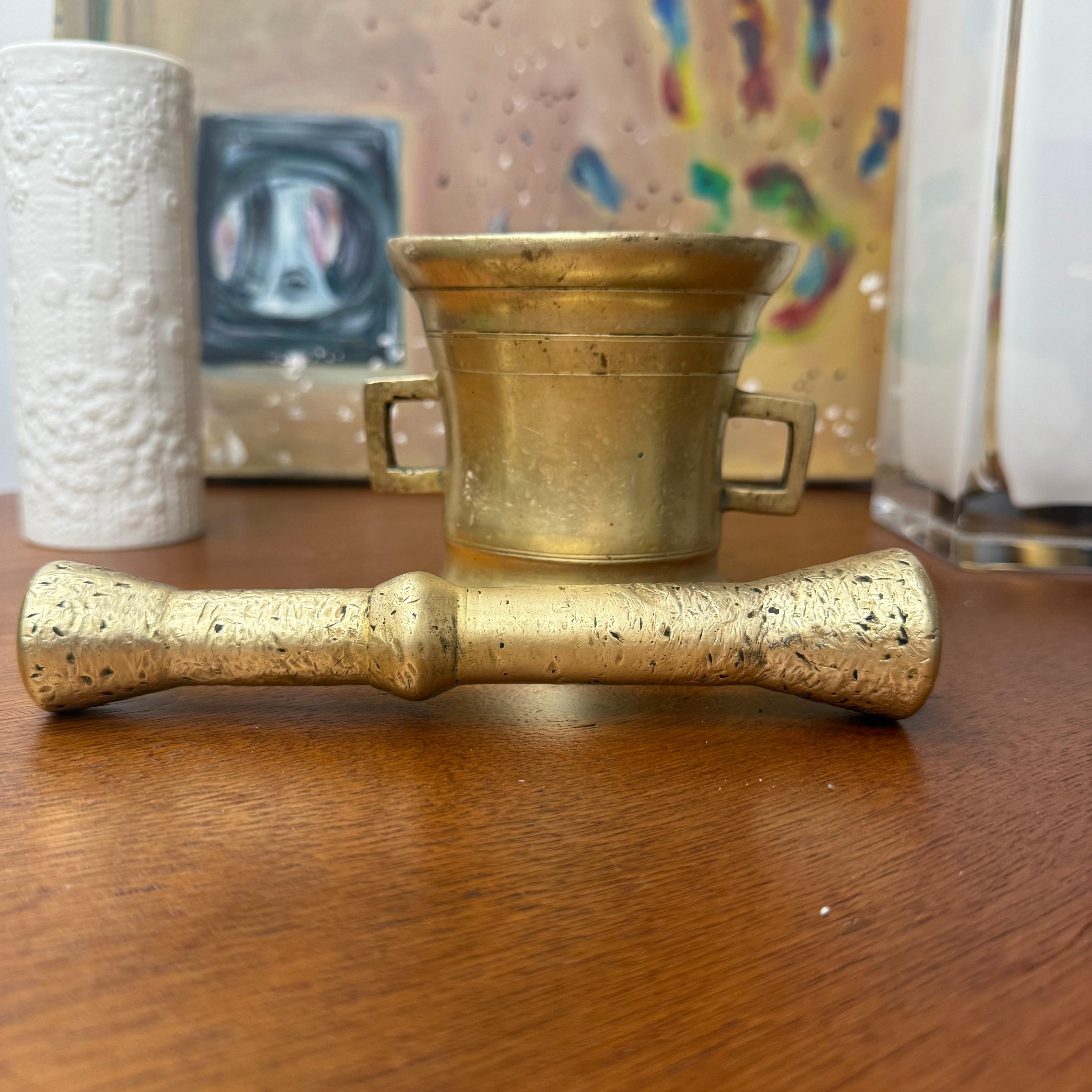 Le corps moulé de forme cylindrique s'élevant jusqu'à un bord évasé, gravé de détails tournés en anneau incisés à l'extérieur, à l'intérieur et sous le corps, entouré de deux poignées ouvertes et de ce qui semble être son pilon d'origine aux